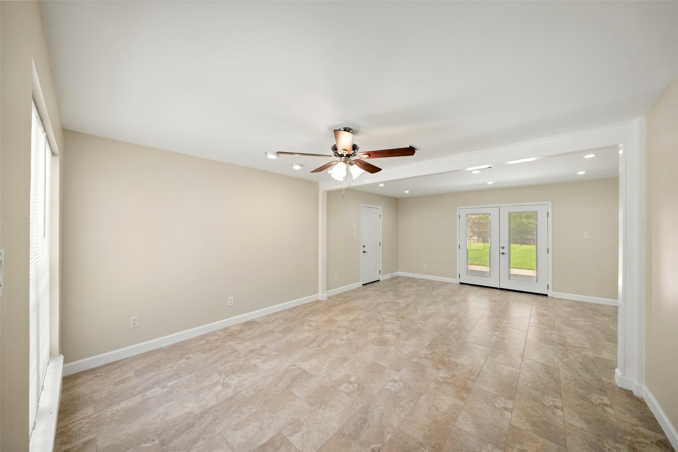 This spacious living room offers a bright, open layout with plenty of flexibility for multiple furniture arrangements and entertaining. Modelo Beige Matte II ceramic tile has been installed throughout, creating a clean and cohesive look. The walls, ceilings, and baseboards have all been freshly painted, giving the space a crisp, move-in-ready finish. Recessed lighting, a ceiling fan, and French doors overlooking the backyard add to the rooms bright and welcoming feel.