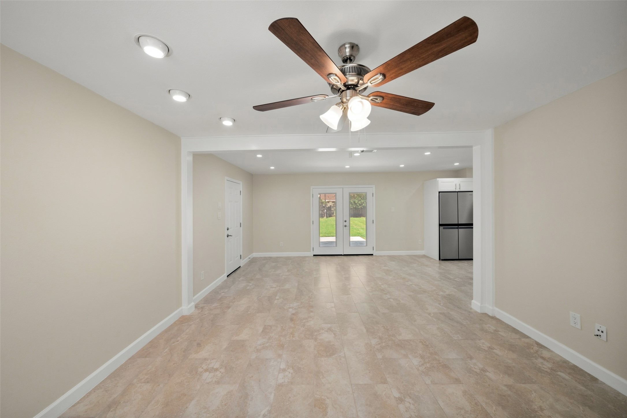This spacious dining area offers a bright, open layout with plenty of room for a full dining set and entertaining. The neutral finishes and recessed lighting create a clean, inviting atmosphere, while the double glass doors provide a direct view of the backyard and allow natural light to flow into the space. The open connection to the adjoining living area gives the room an easy, comfortable feel for everyday meals and gatherings.