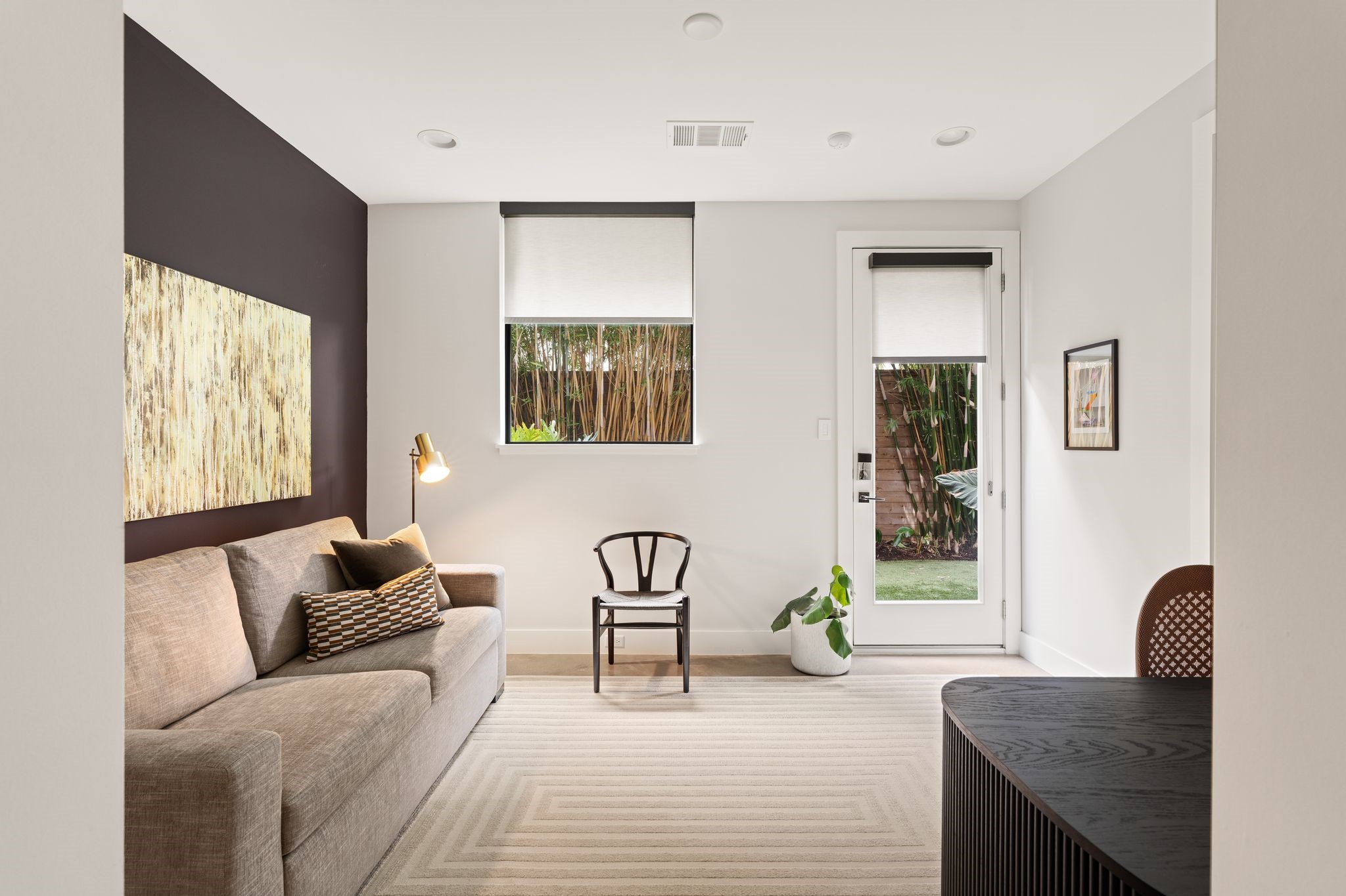 Versatile first-floor bedroom with high ceilings and direct backyard access, currently styled as an office and lounge and equally suited for overnight guests.