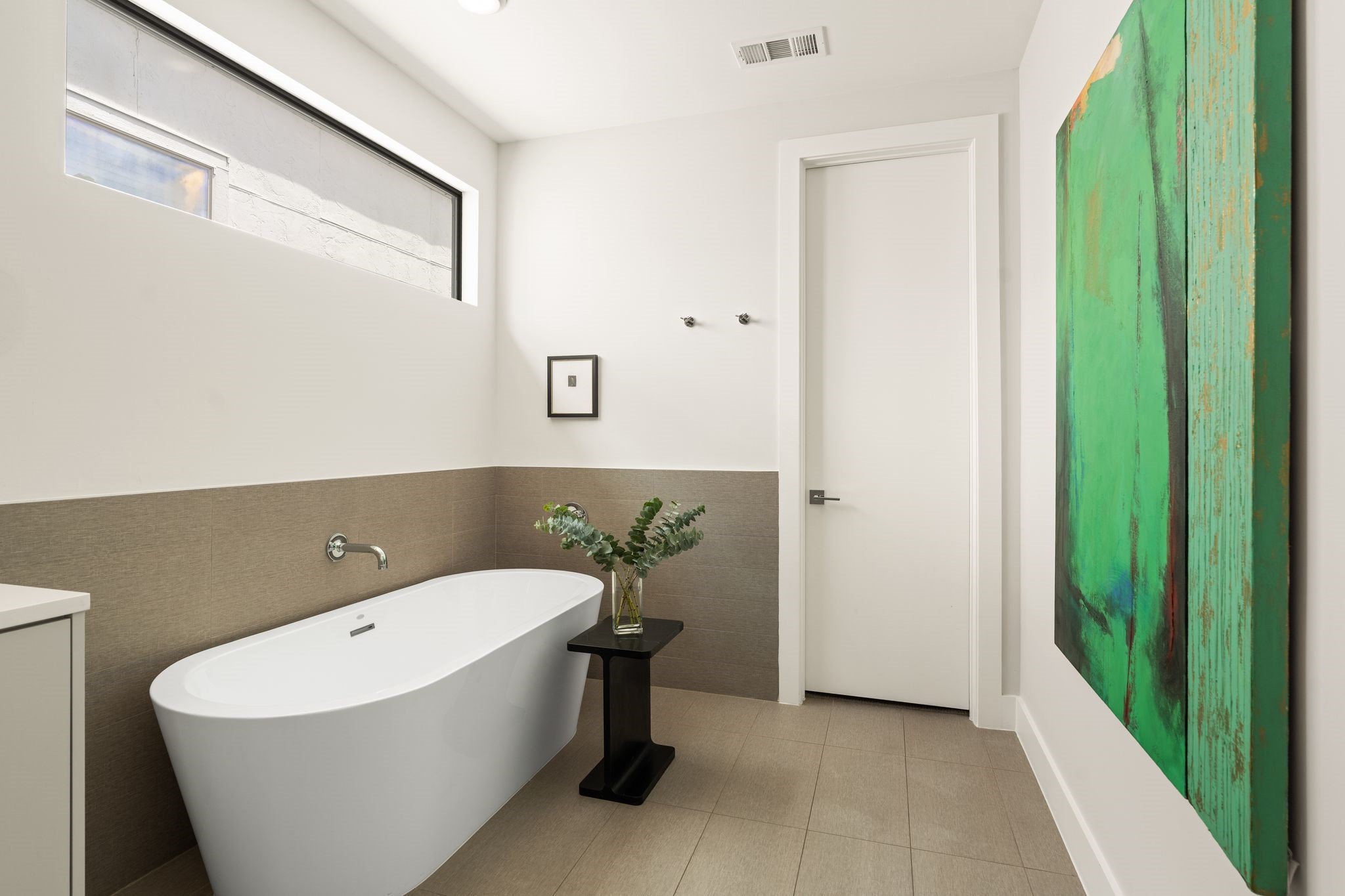 Spa-inspired primary bathroom features a freestanding soaking tub, generous wall space for artwork, and direct access to the expansive walk-in closet.