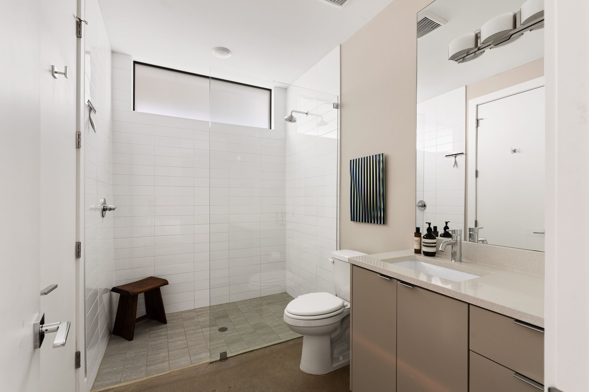 Sleek first-floor full bath with a glass-enclosed walk-in shower, contemporary finishes, and a spacious vanity with abundant cabinetry and drawer storage.