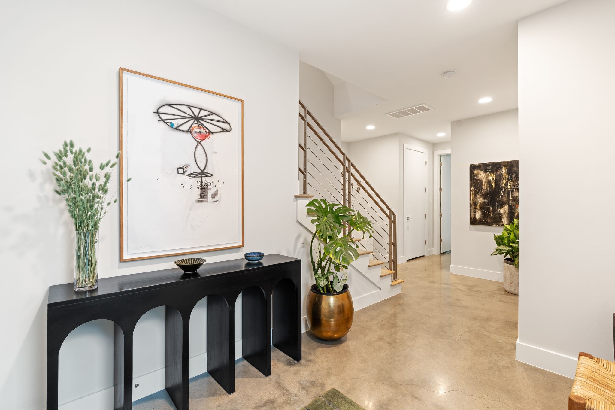 A generous foyer creates a sophisticated arrival with polished concrete floors, contemporary stair detailing, and ample space for furnishings or art.