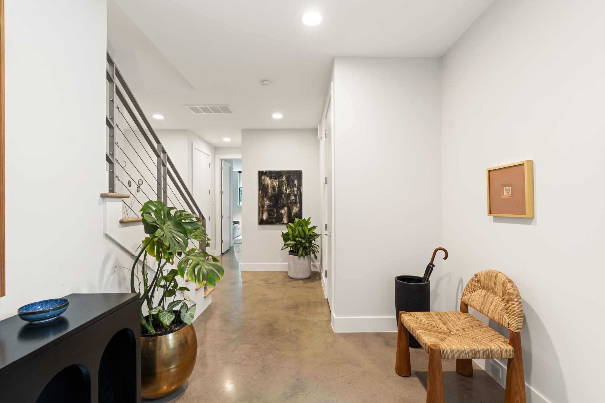 Spacious first-floor entry with design-forward concrete floors, high ceilings, and convenient access to the garage and two secondary bedrooms.