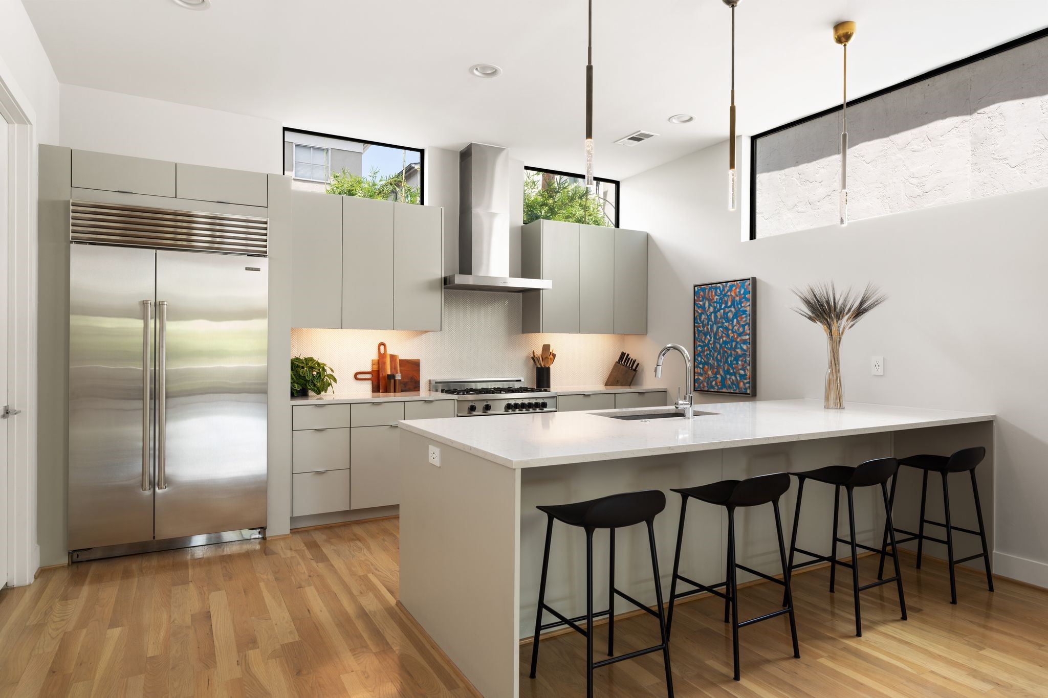 Elevated kitchen featuring an upgraded built-in Sub-Zero refrigerator, custom cabinetry, hardwood floors, and a streamlined contemporary aesthetic.