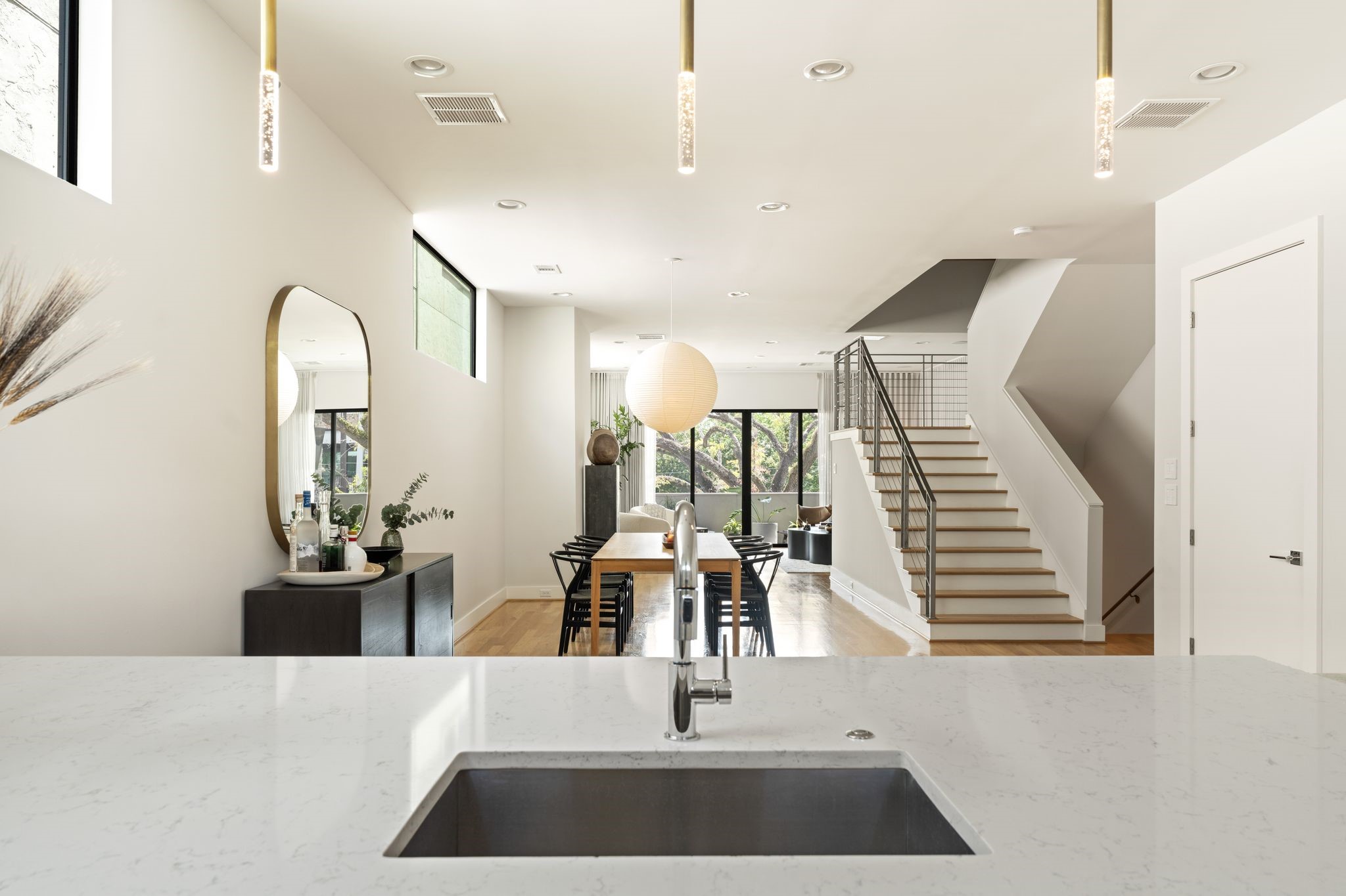 View from the kitchen illustrates the effortless open-concept flow through the dining area to the light-filled living room beyond.