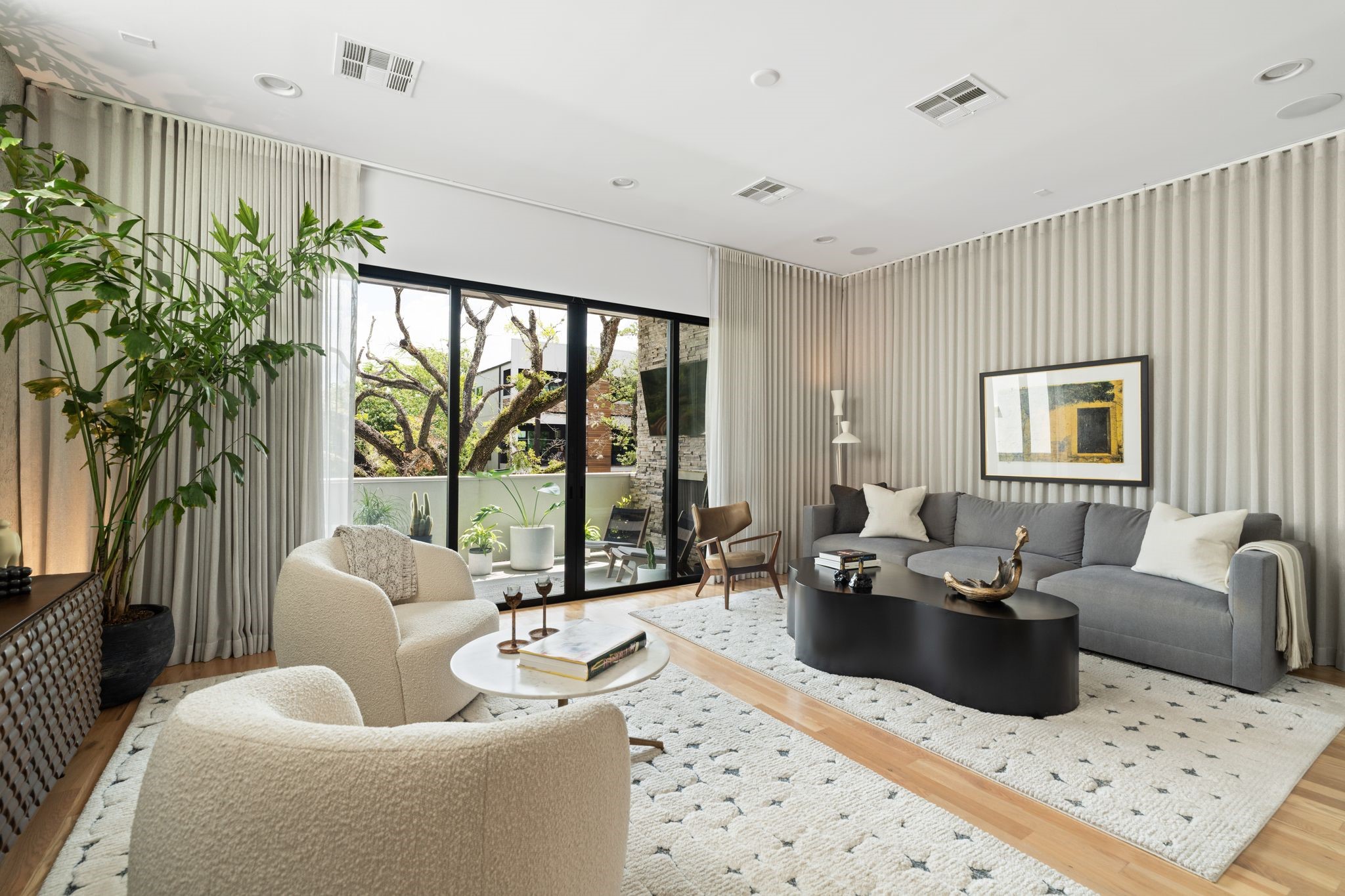 Sophisticated Upper Kirby living space with hardwood floors, custom designer drapery, integrated audio and expansive glass doors connecting the interiors to the tree-lined covered terrace. Sophisticated Upper Kirby living space with hardwood floors, custom designer drapery, integrated audio and expansive glass doors connecting the interiors to the tree-lined covered terrace.