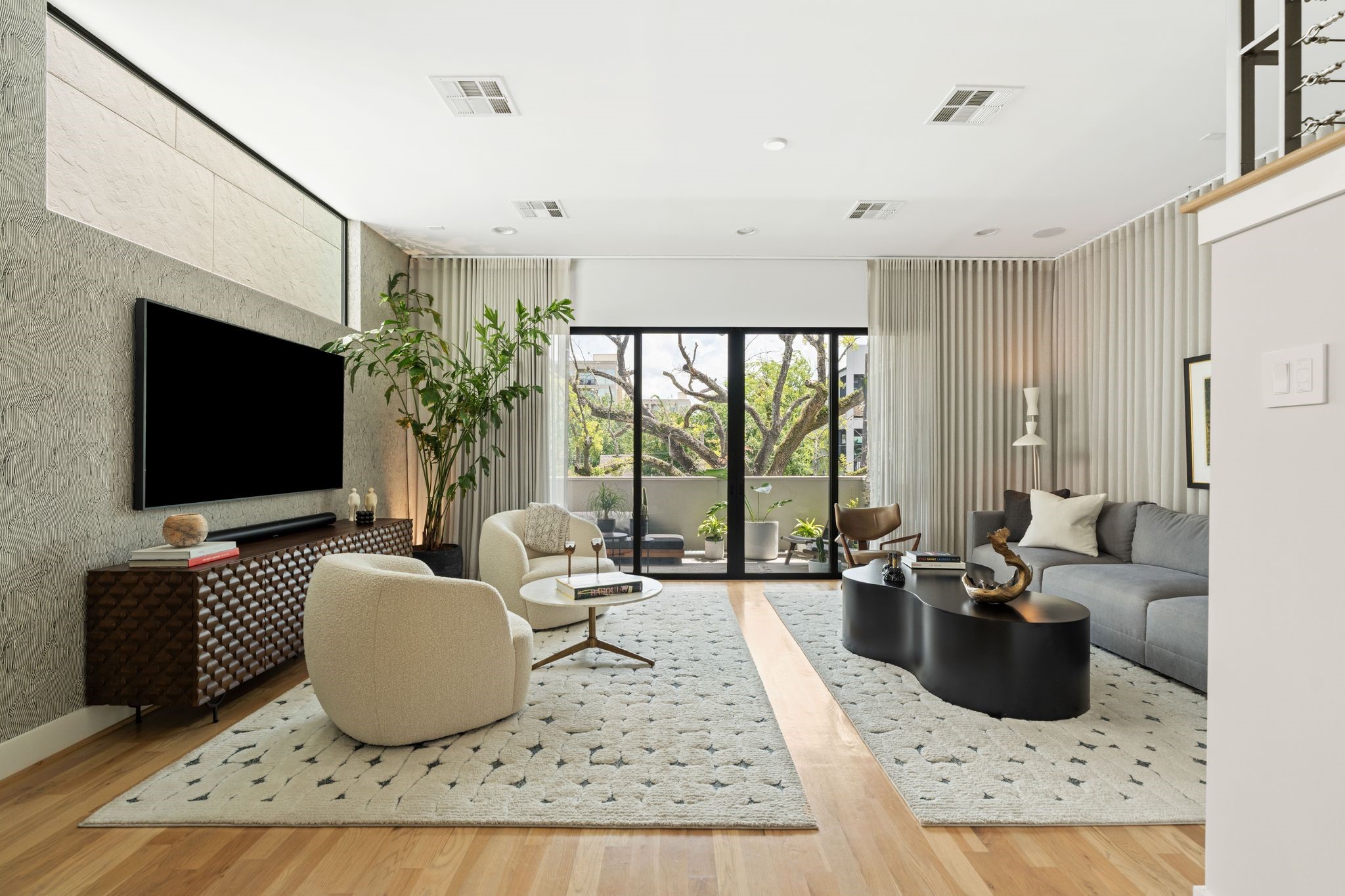Light-filled living room with hardwood floors, high ceilings, expansive sliding glass doors, and direct access to the covered outdoor terrace.
