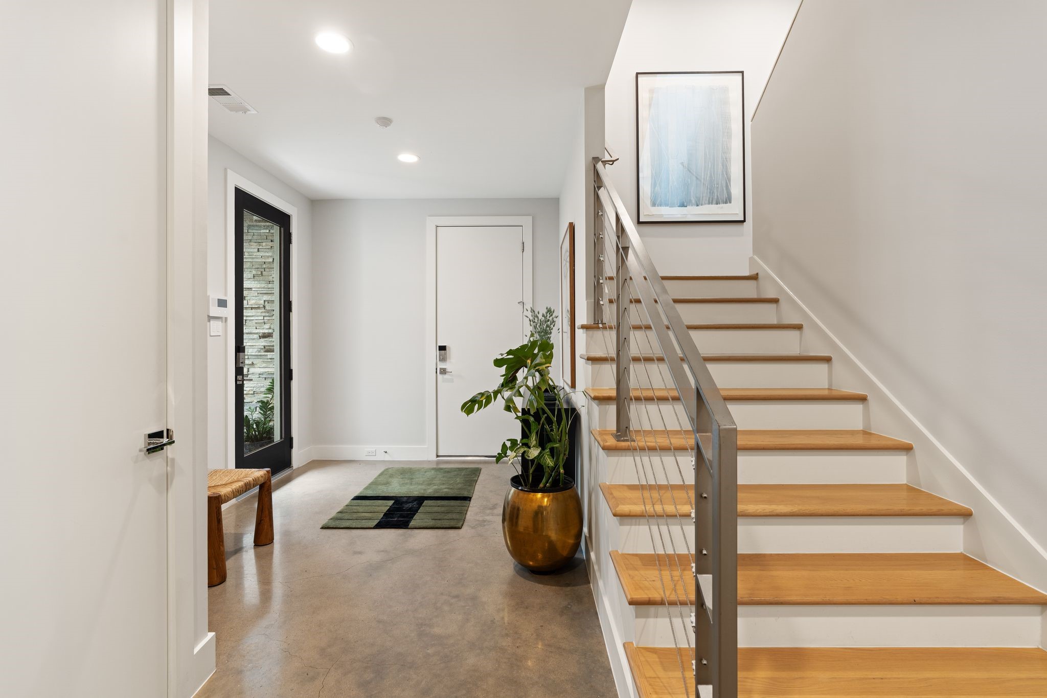Contemporary stairway leads from the first-floor entry to the homes light-filled second-floor living and entertaining spaces.