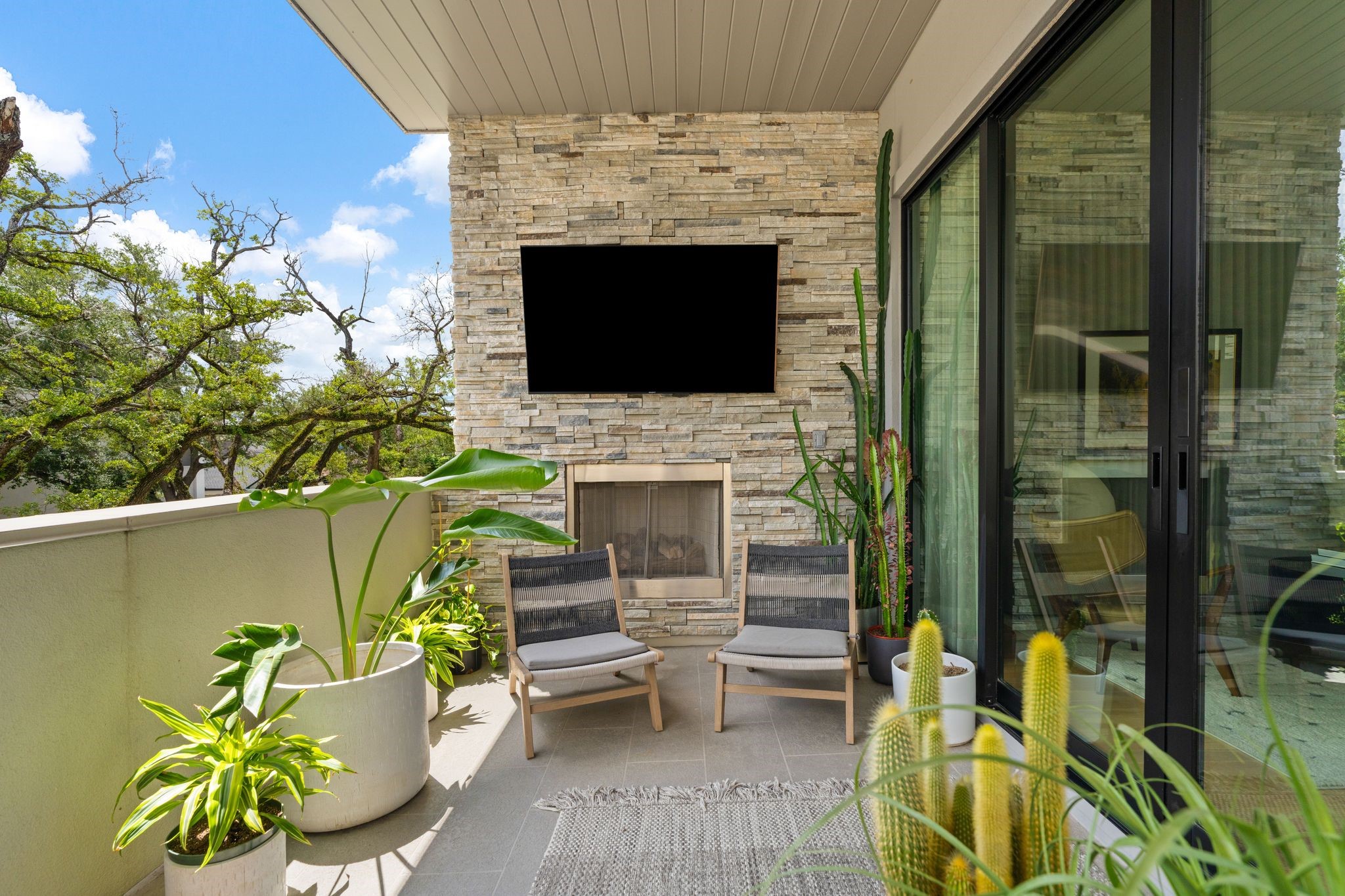 Covered second-floor terrace with fireplace, television, built-in audio, and direct access to the living room creates an inviting extension of the homes entertaining spaces.