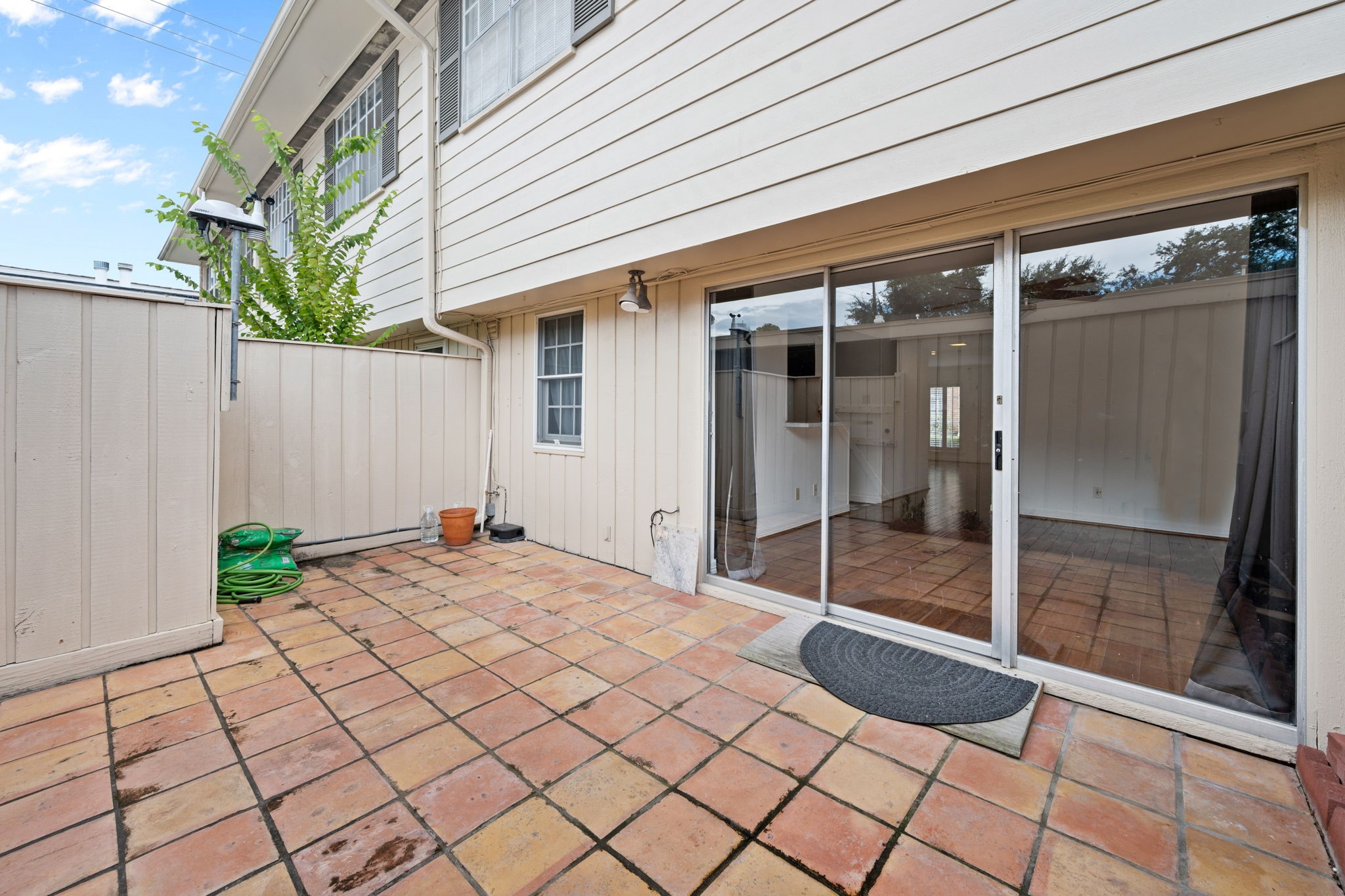 Charming private patio with terracotta tile flooring, perfect for outdoor relaxation, featuring sliding glass doors that open to a cozy interior space.