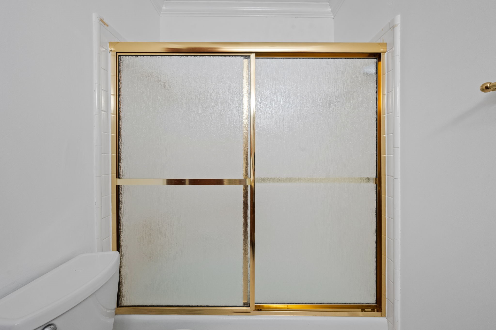 Elegant bathroom with a frosted glass shower door framed in gold, offering a touch of luxury and privacy.