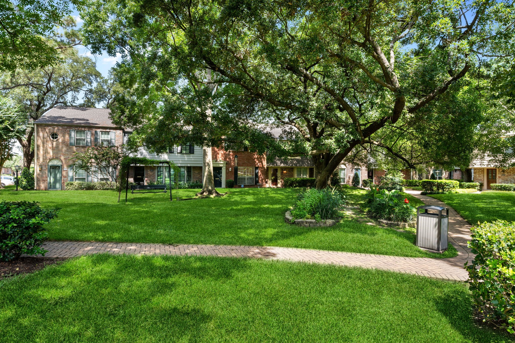 Charming townhomes surrounded by lush greenery and mature trees, offering a serene community atmosphere with well-maintained pathways and inviting outdoor spaces.
