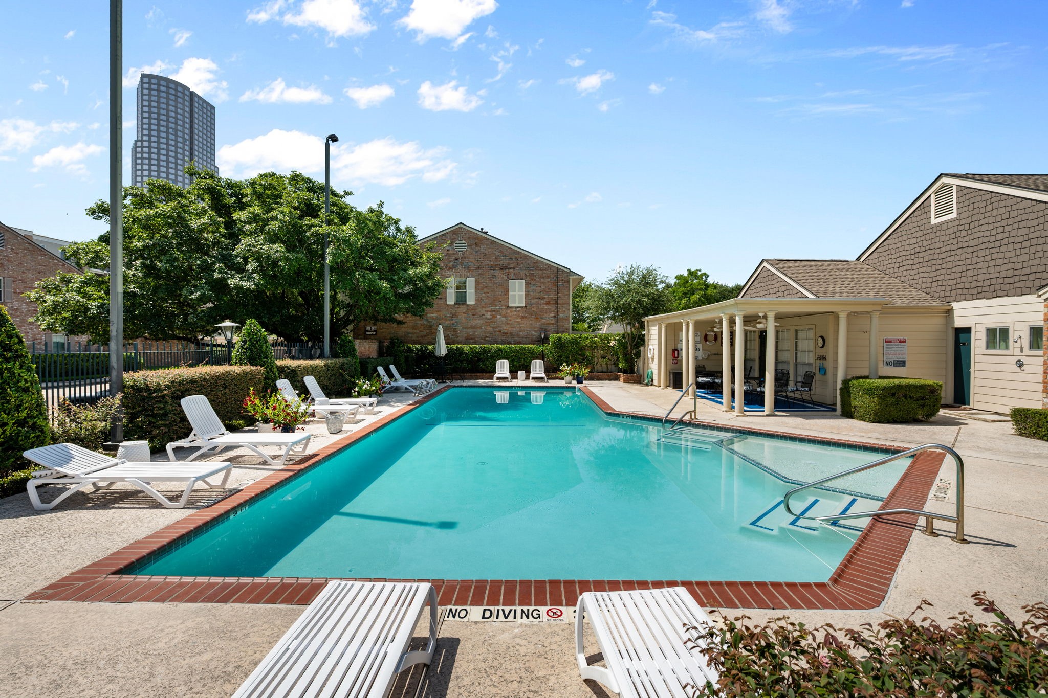 Relax by the sparkling outdoor pool, surrounded by comfortable lounge chairs and lush greenery, perfect for sunny afternoons.