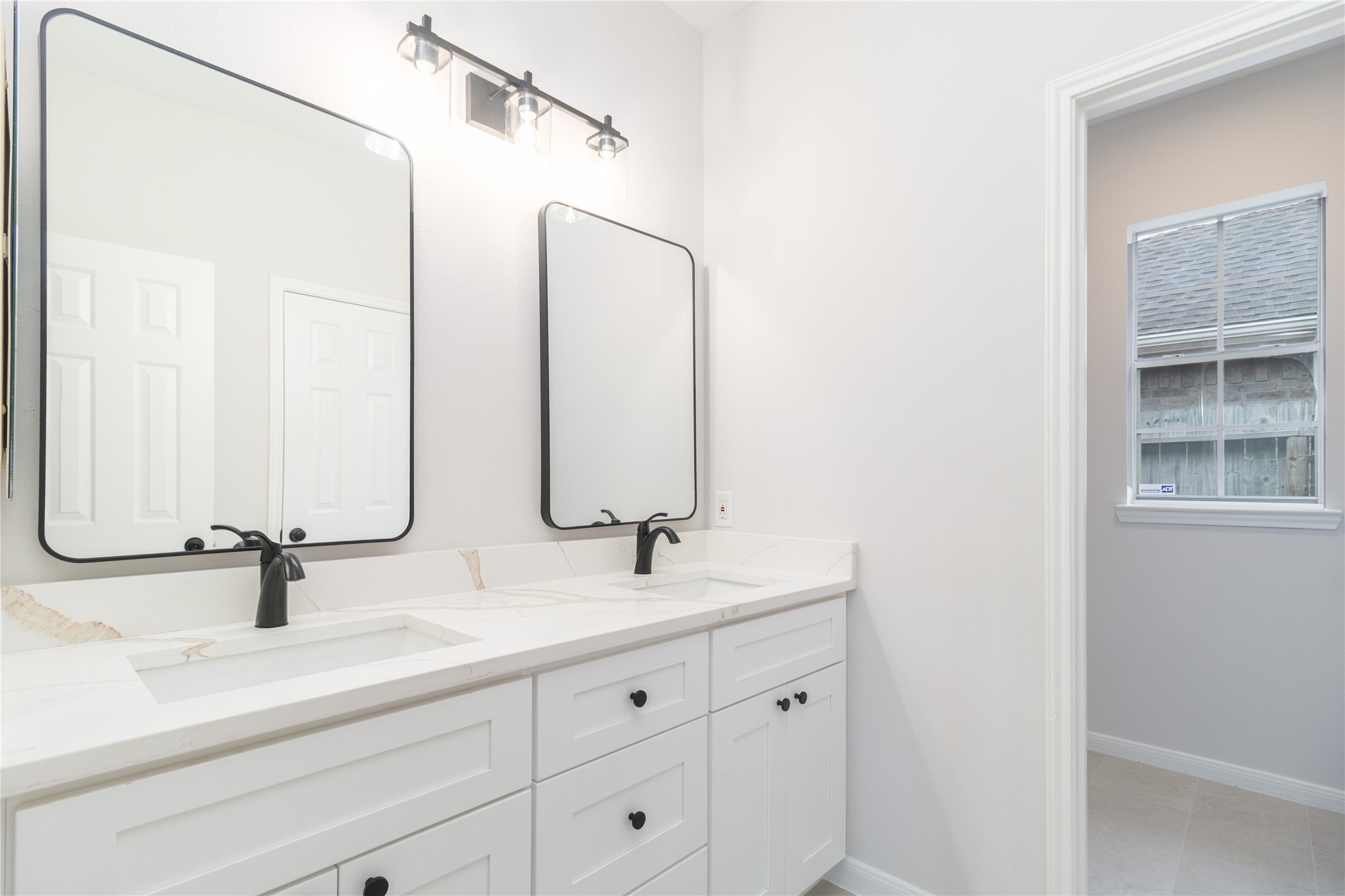 Full bath with new cabinets, quartz tops, mirrors, and fixtures.