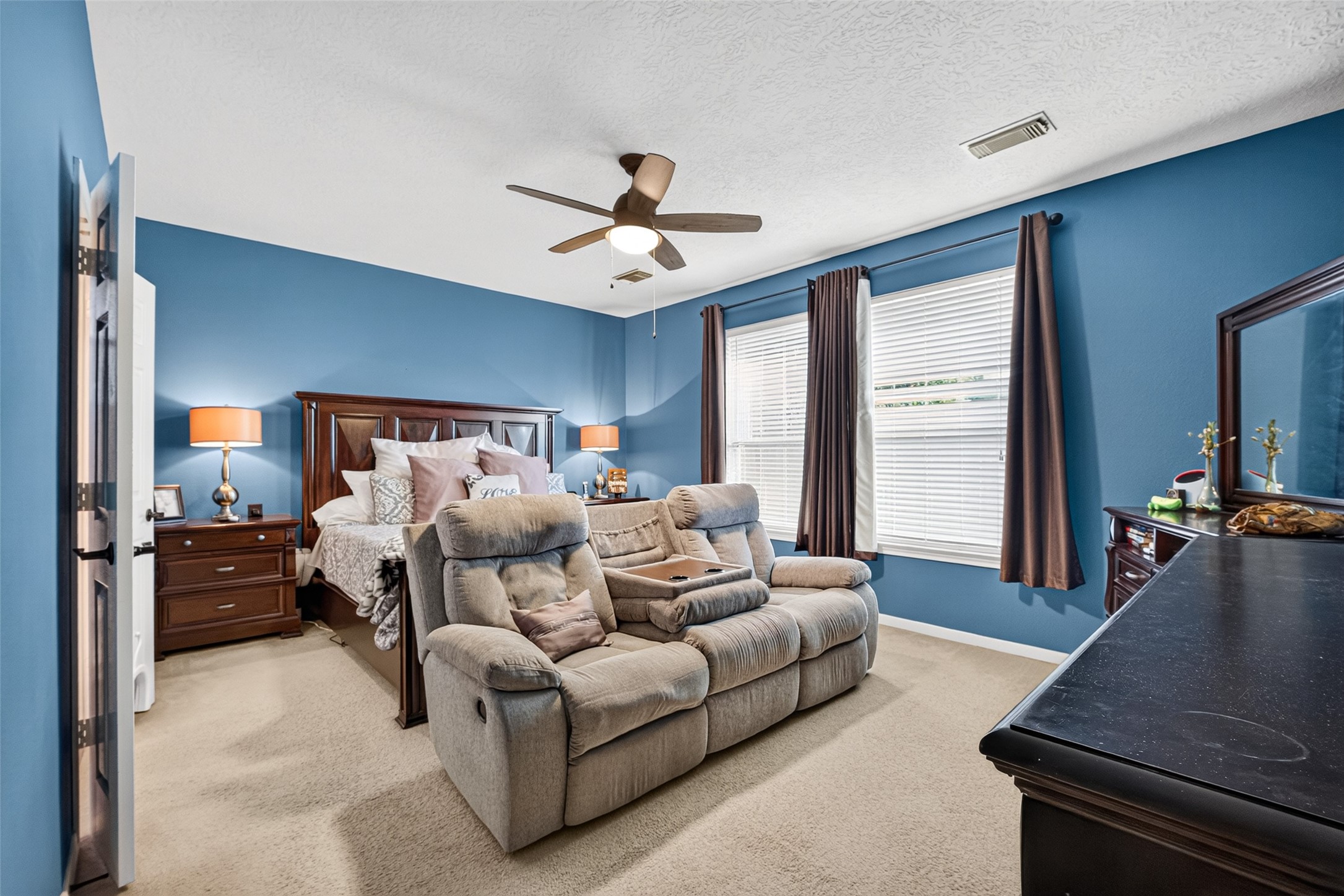 Relaxing primary suite with sitting area and large windows.