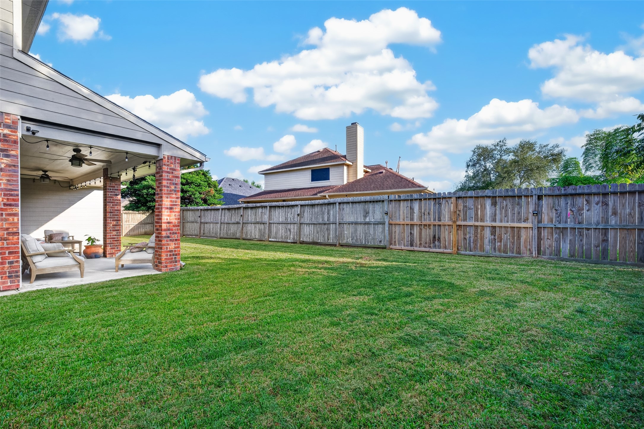 Fully fenced backyard stretching out behind the covered patio.