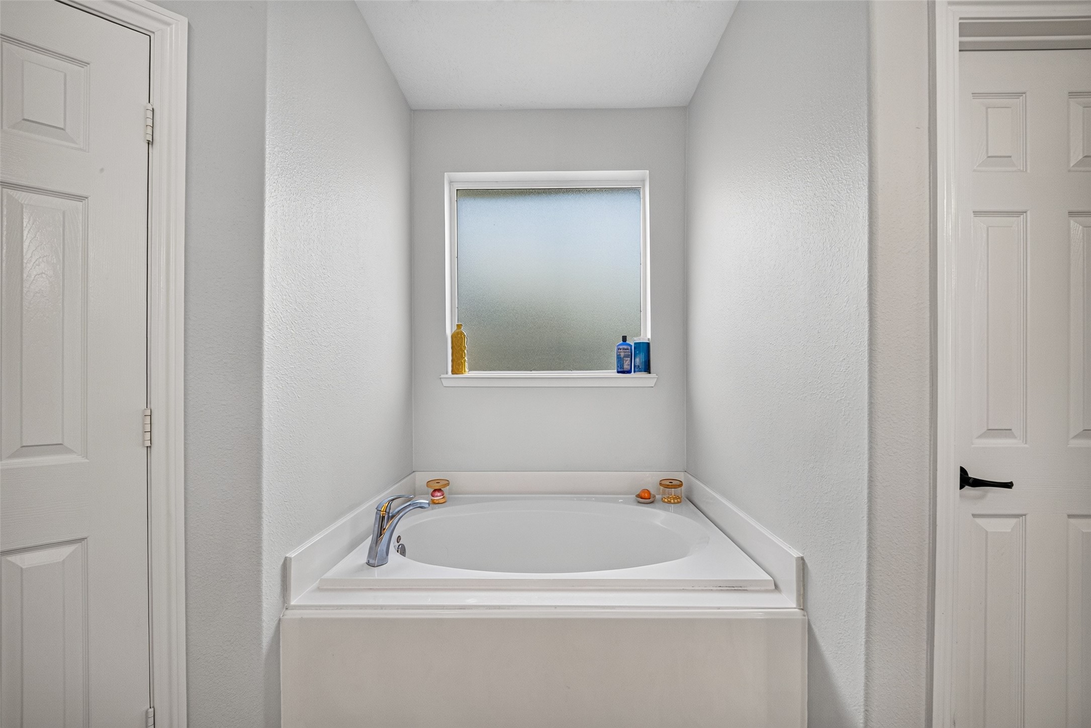Soaking garden tub set beneath a bright window.