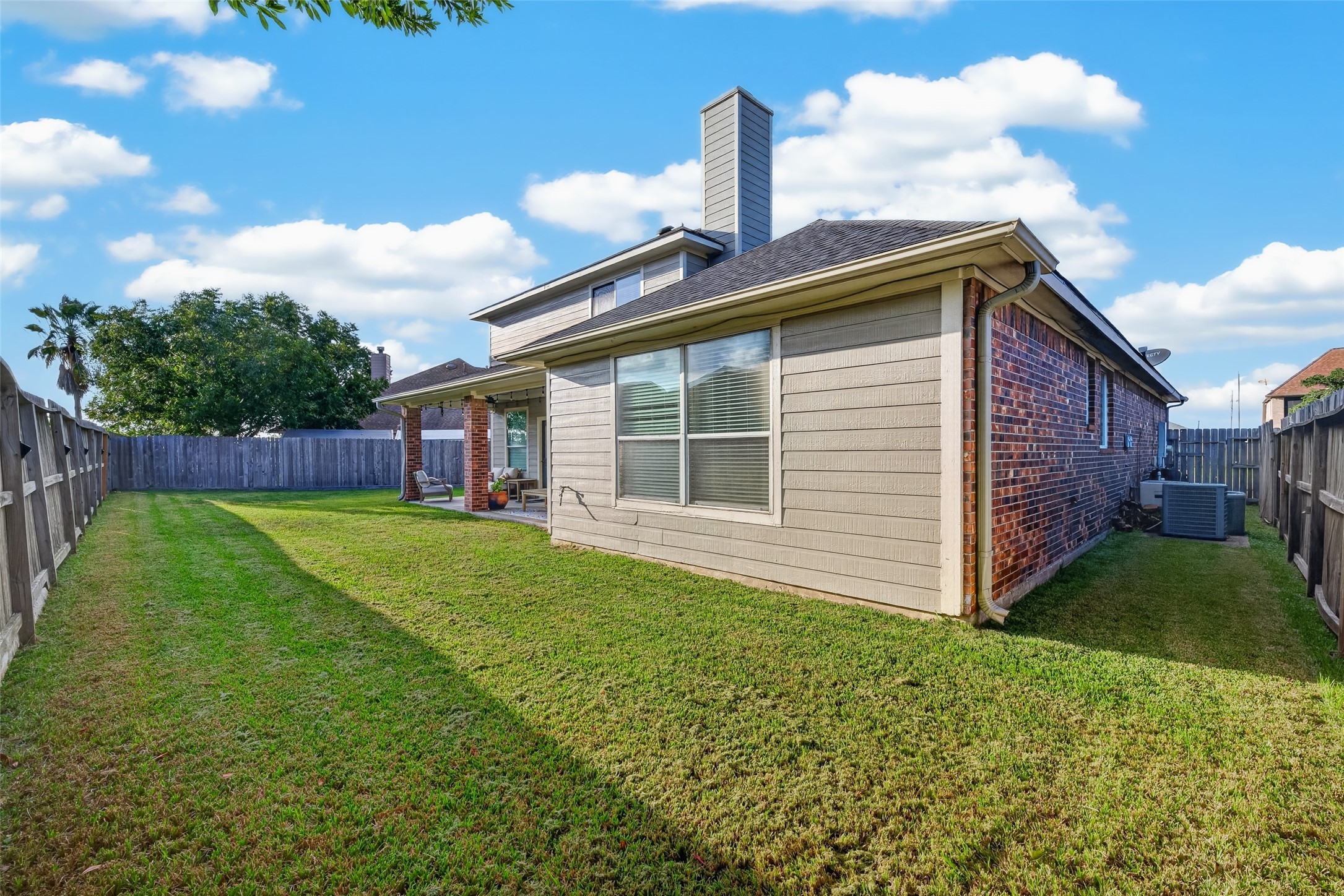 Rear view of the two-story brick home and its lawn.