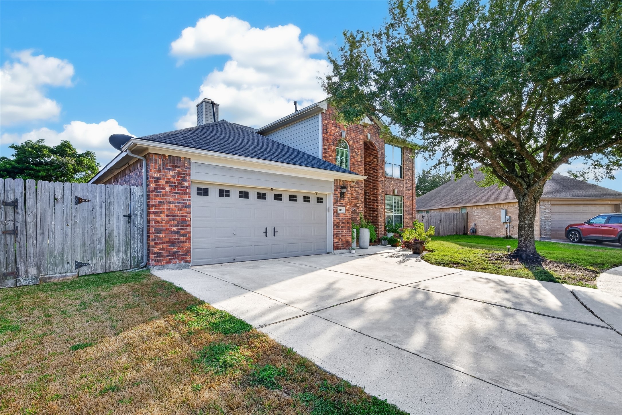 Classic brick two-story with a wide driveway and mature shade tree out front. Classic brick two-story with a wide driveway and mature shade tree out front.