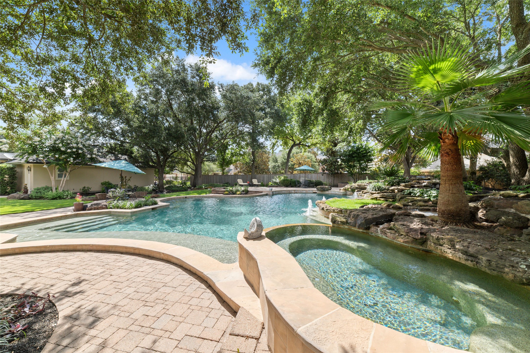 Mature trees provide ample shade, and the stone accents add a touch of elegance, making it a perfect place for relaxation and entertaining.