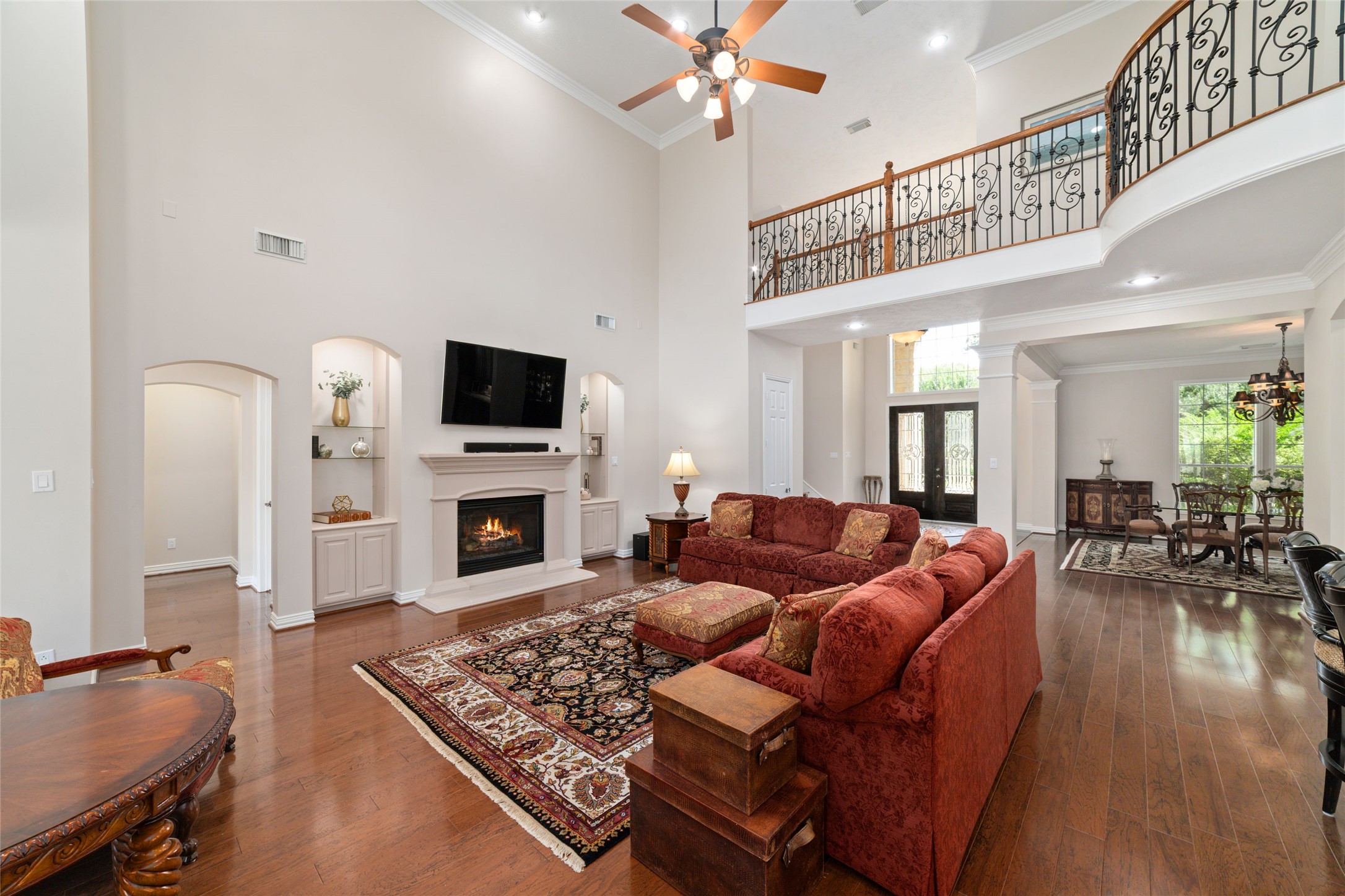 Spacious living room boasts high ceilings and a cozy fireplace. The open layout seamlessly connects to the formal dining area, which is filled with natural light from large windows. Its an ideal space for entertaining guests and hosting family gatherings.