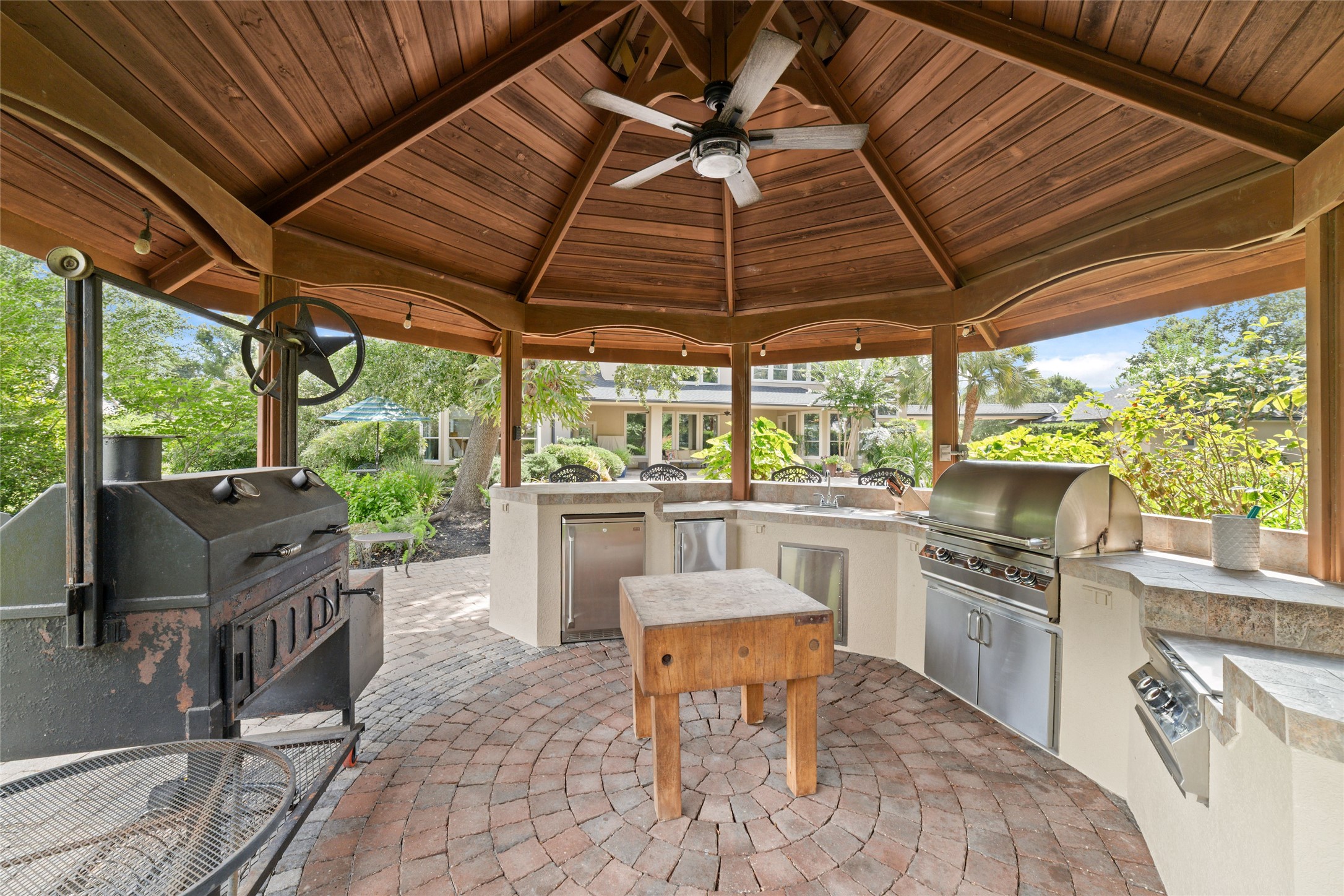 This outdoor kitchen features a covered gazebo with ice maker, mini fridge, ampl counter space, perfect for entertaining.