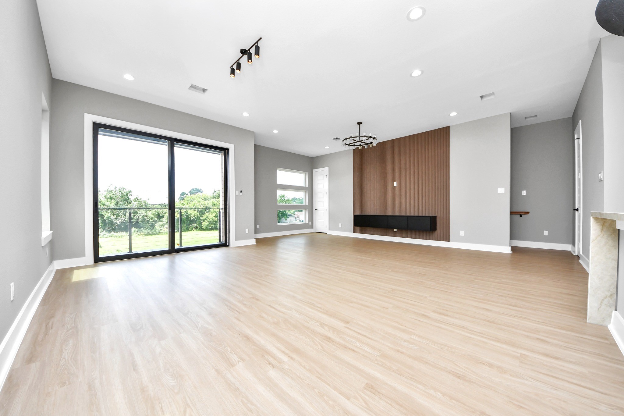 The actual vacant view reveals the generous scale, designer lighting, modern feature wall and abundant natural light.