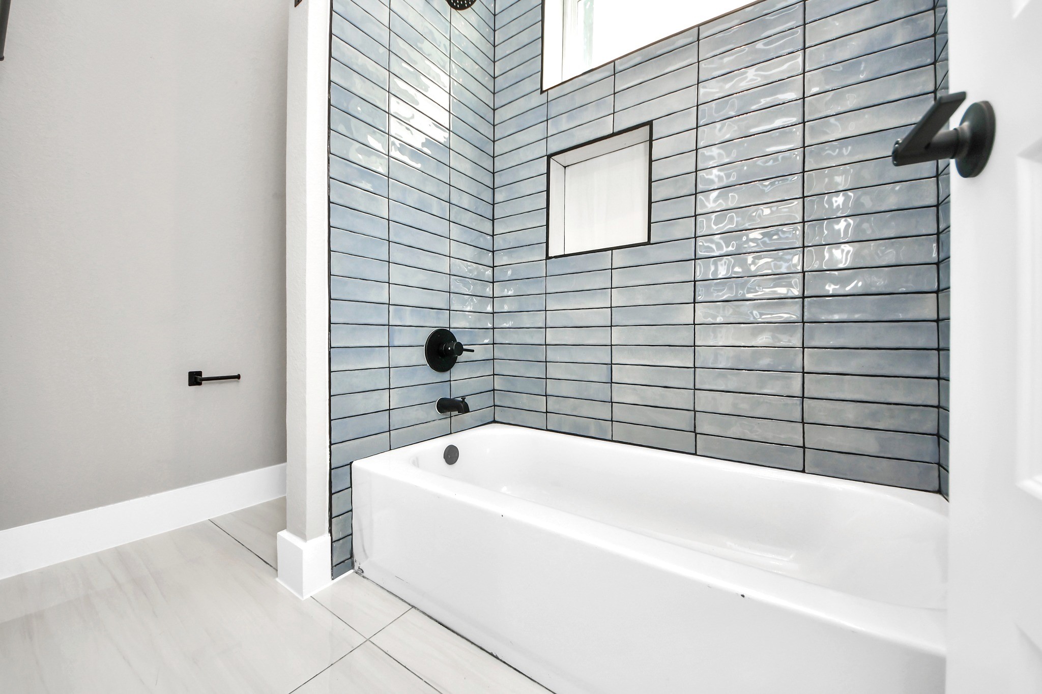 The secondary bathroom pairs a full tub and shower with modern tilework and clean contemporary details.
