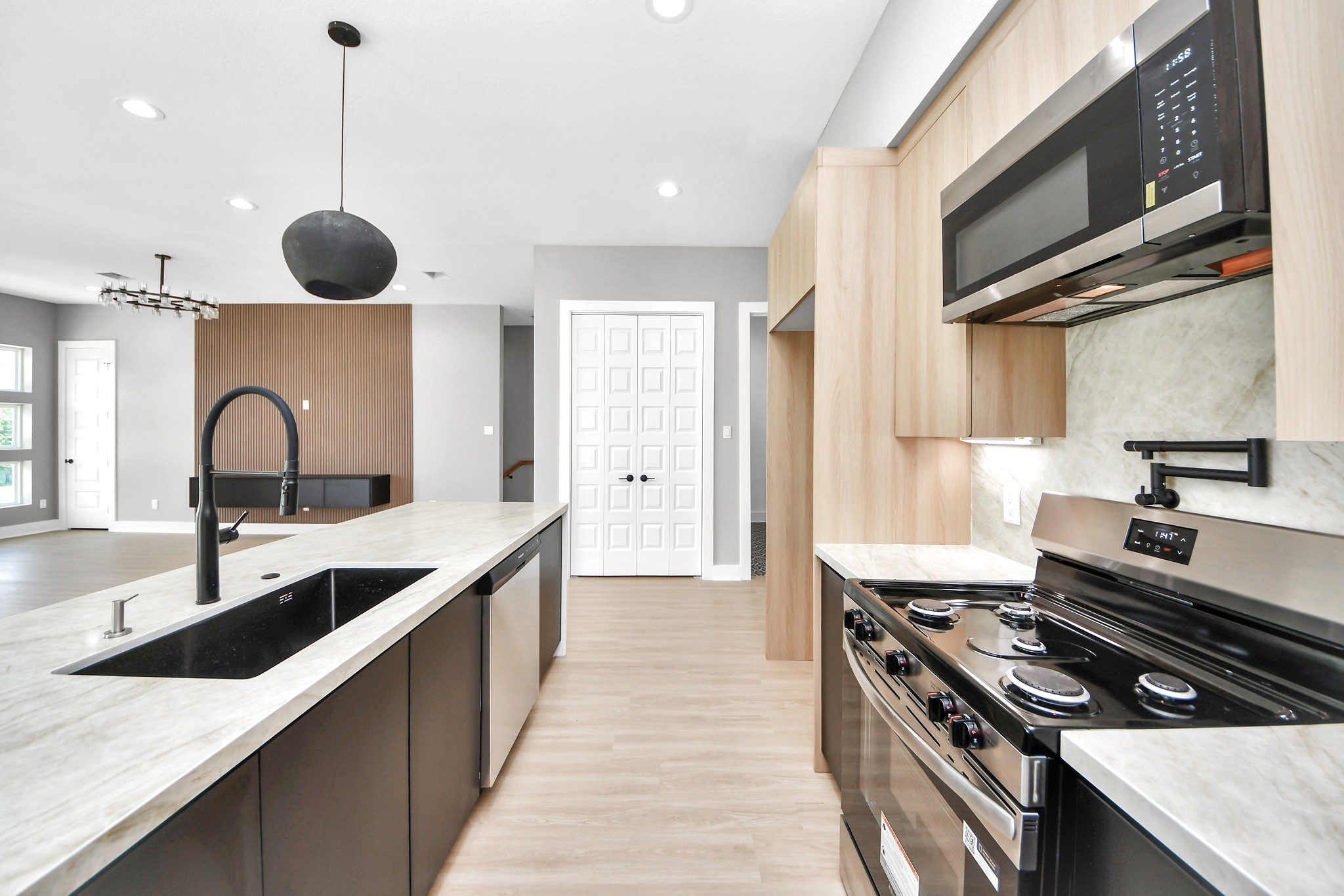 Warm cabinetry, sleek black accents, stone surfaces and stainless appliances deliver a polished modern finish.