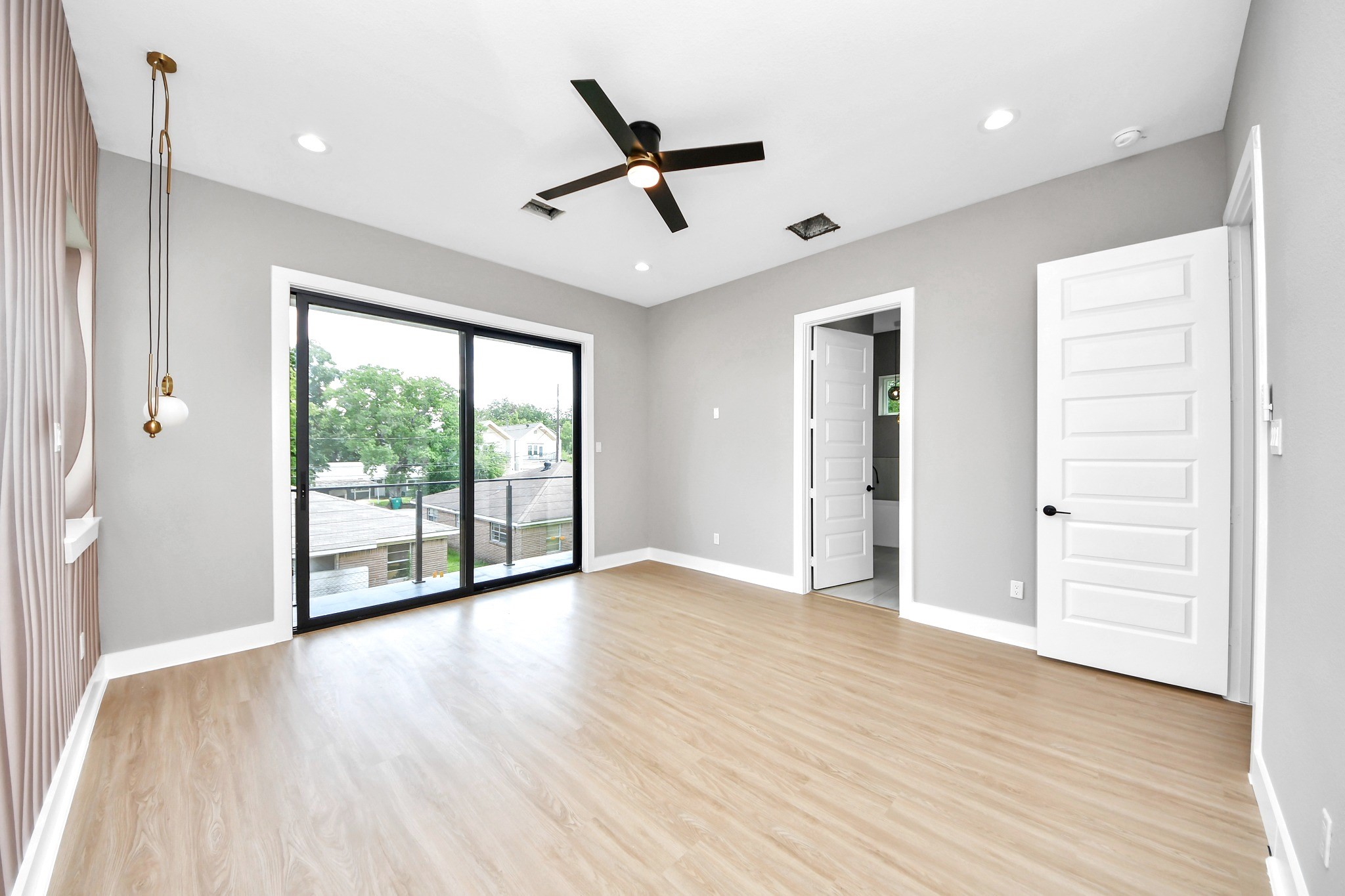 The vacant primary-bedroom view shows the true room dimensions, statement wall, modern sconces and balcony connection.