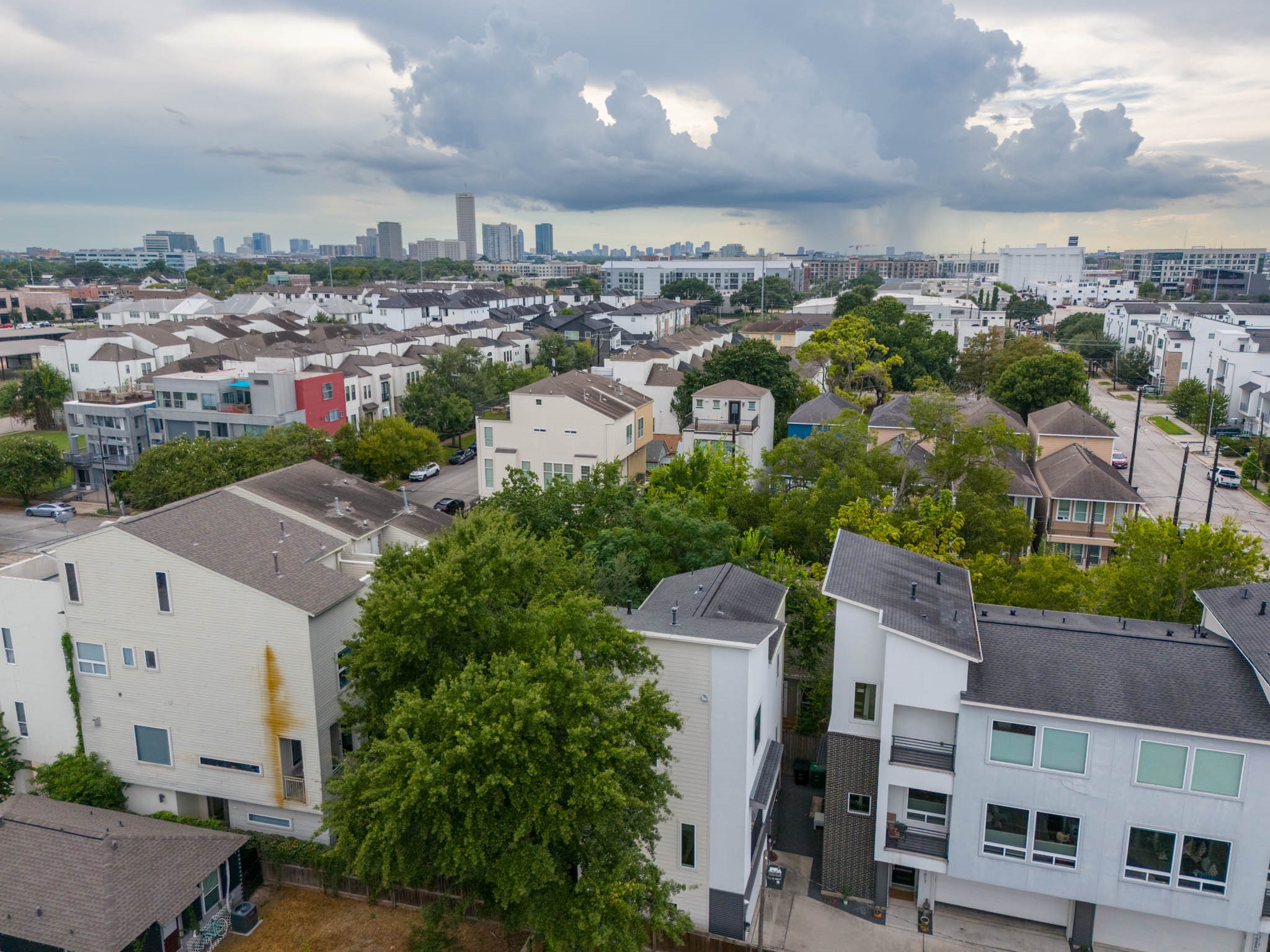 Modern townhomes nestled in a vibrant neighborhood, surrounded by lush greenery and offering a stunning skyline view.