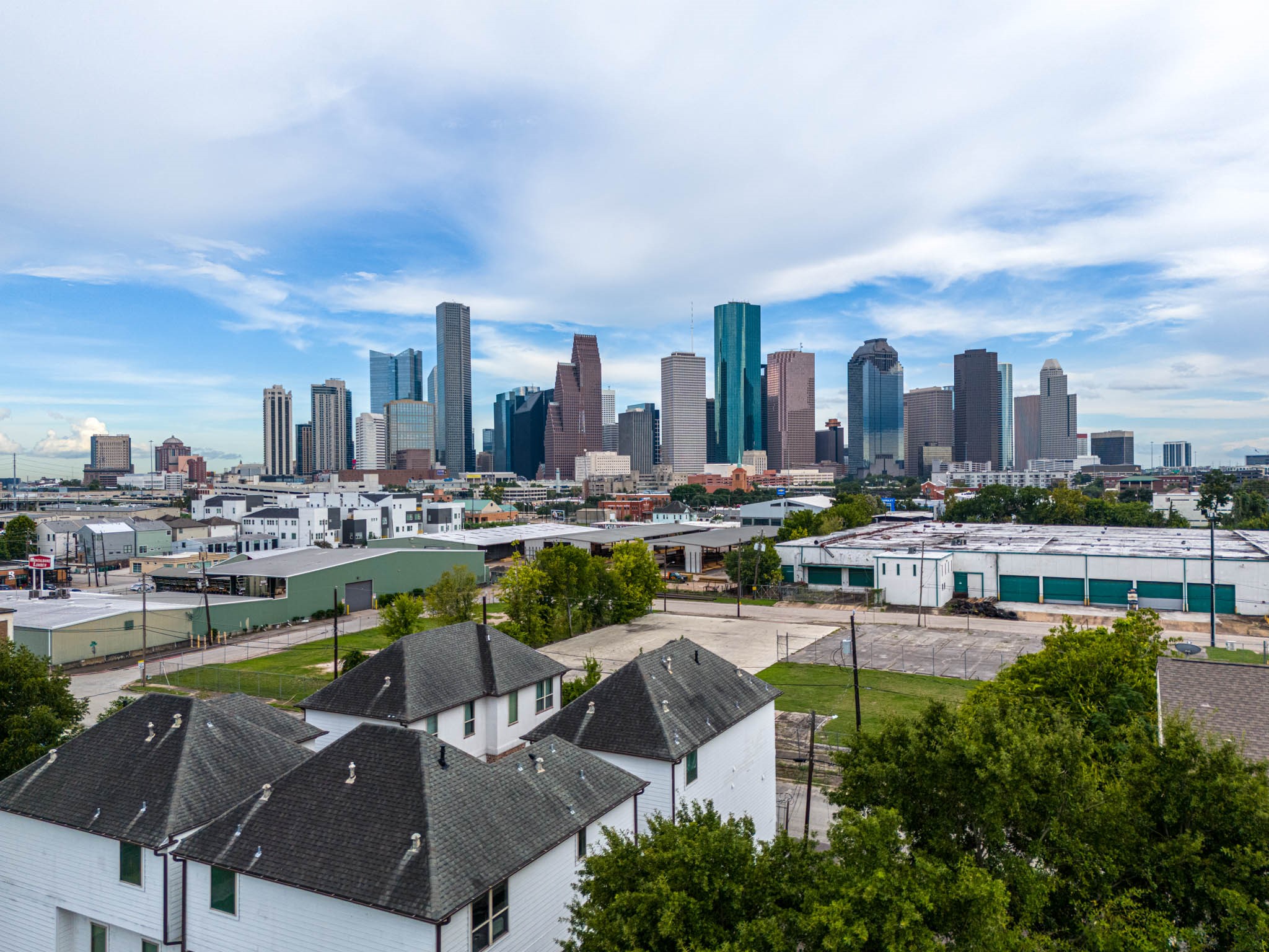 Stunning skyline views of downtown Houston, showcasing a blend of modern architecture and vibrant city life, with residential rooftops in the foreground.