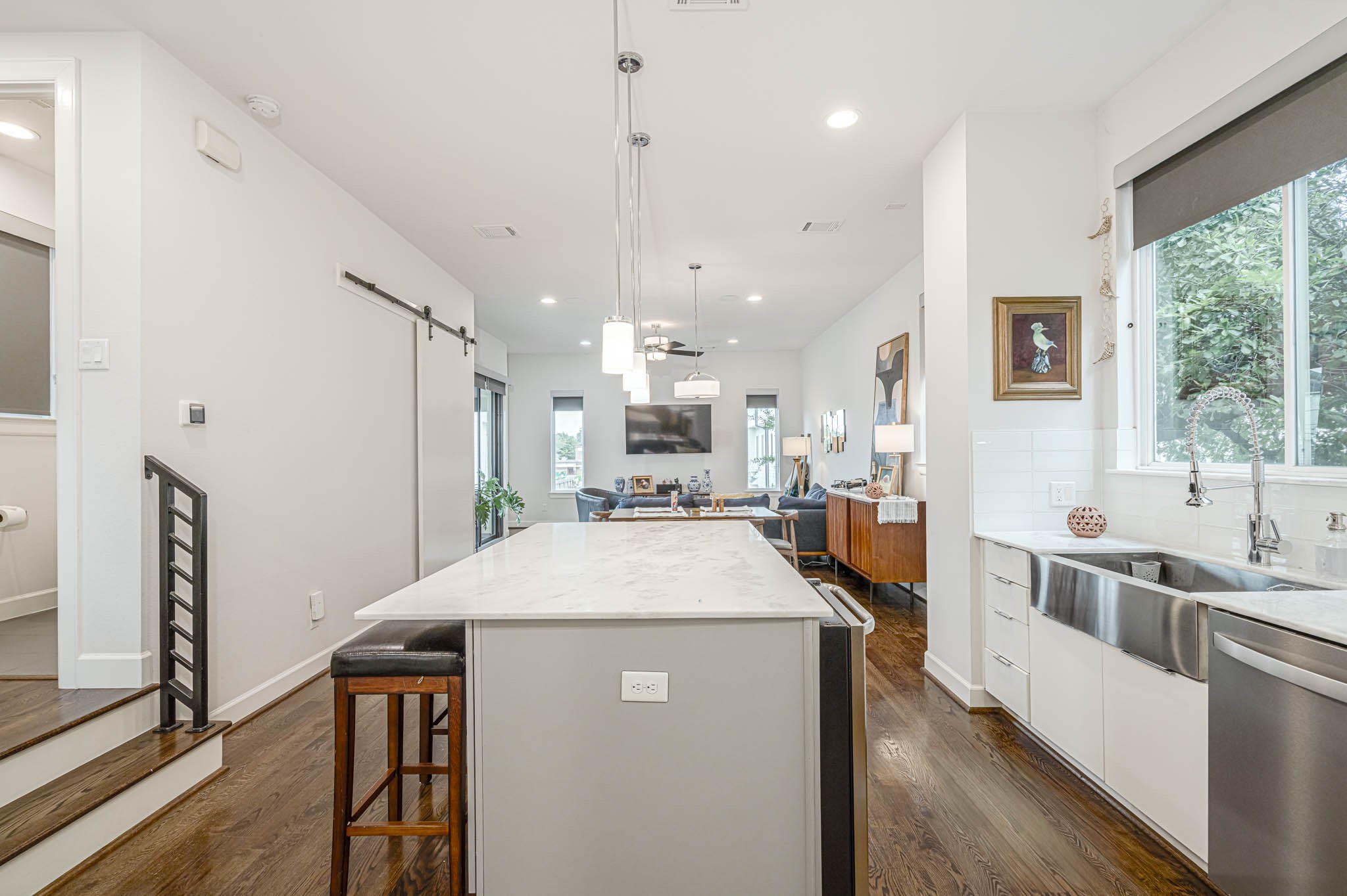 Modern kitchen with a sleek marble island, stainless steel farmhouse sink, and open layout leading to a cozy living area.