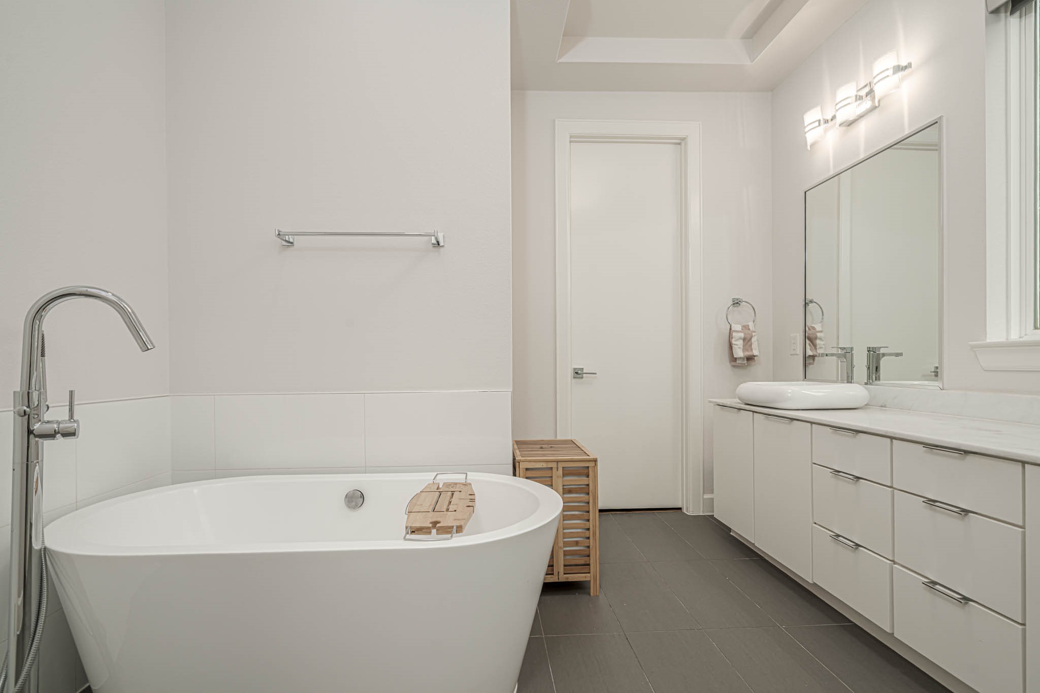 luxurious primary bathroom, featuring a sleek freestanding tub, modern fixtures, and elegant cabinetry.