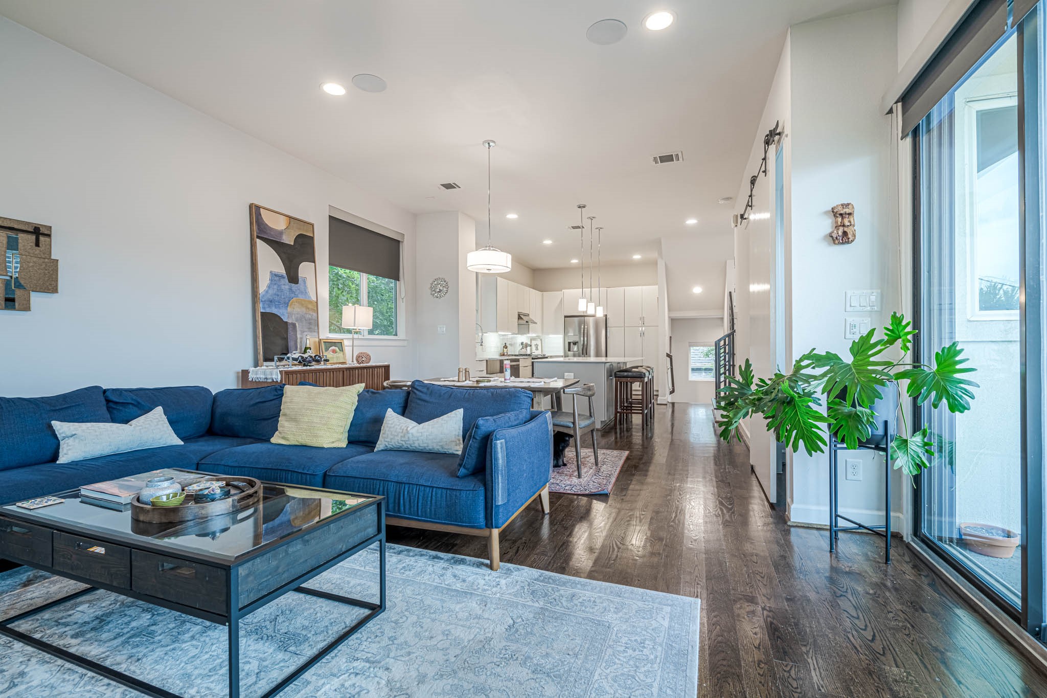 Spacious open-concept living area with sleek hardwood floors, a modern kitchen, and abundant natural light from large sliding glass doors. Ideal for entertaining or relaxing.