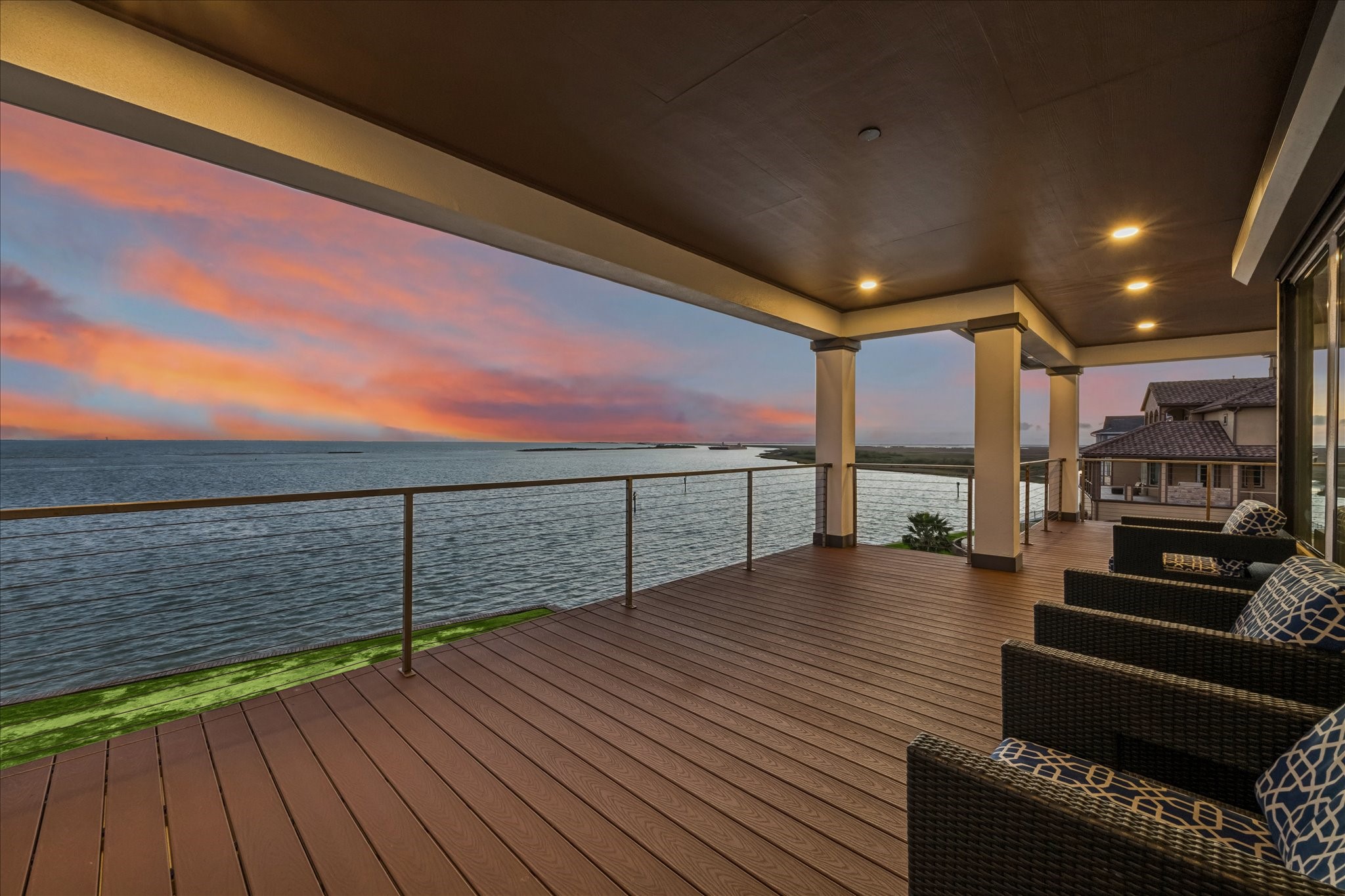 The spacious covered balcony just off the main living area offers unobstructed views of West Galveston Bay. New composite decking provides a lifetime of low maintenance, while sleek cable railings and a covered ceiling with recessed lighting create a stylish, all-weather outdoor space