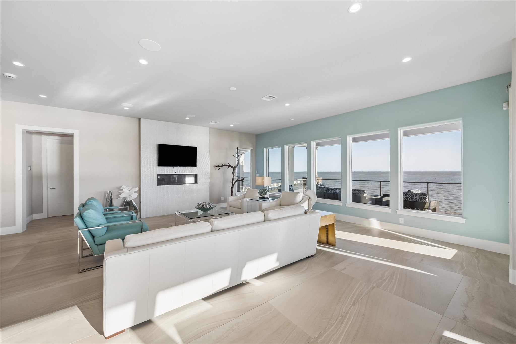 Large-scale windows frame the surrounding coastal views, blurring the lines between the indoor sanctuary and the outdoor balconies