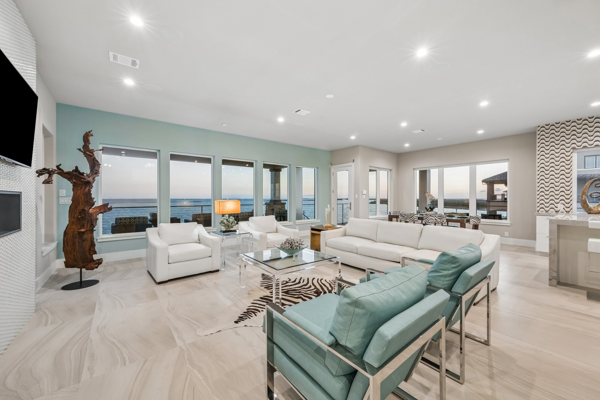 This light filled living area features large 24" x 48" tile flooring throughout, high ceilings with recessed lighting, and modern comfort, all complemented by a wall of windows capturing the stunning views