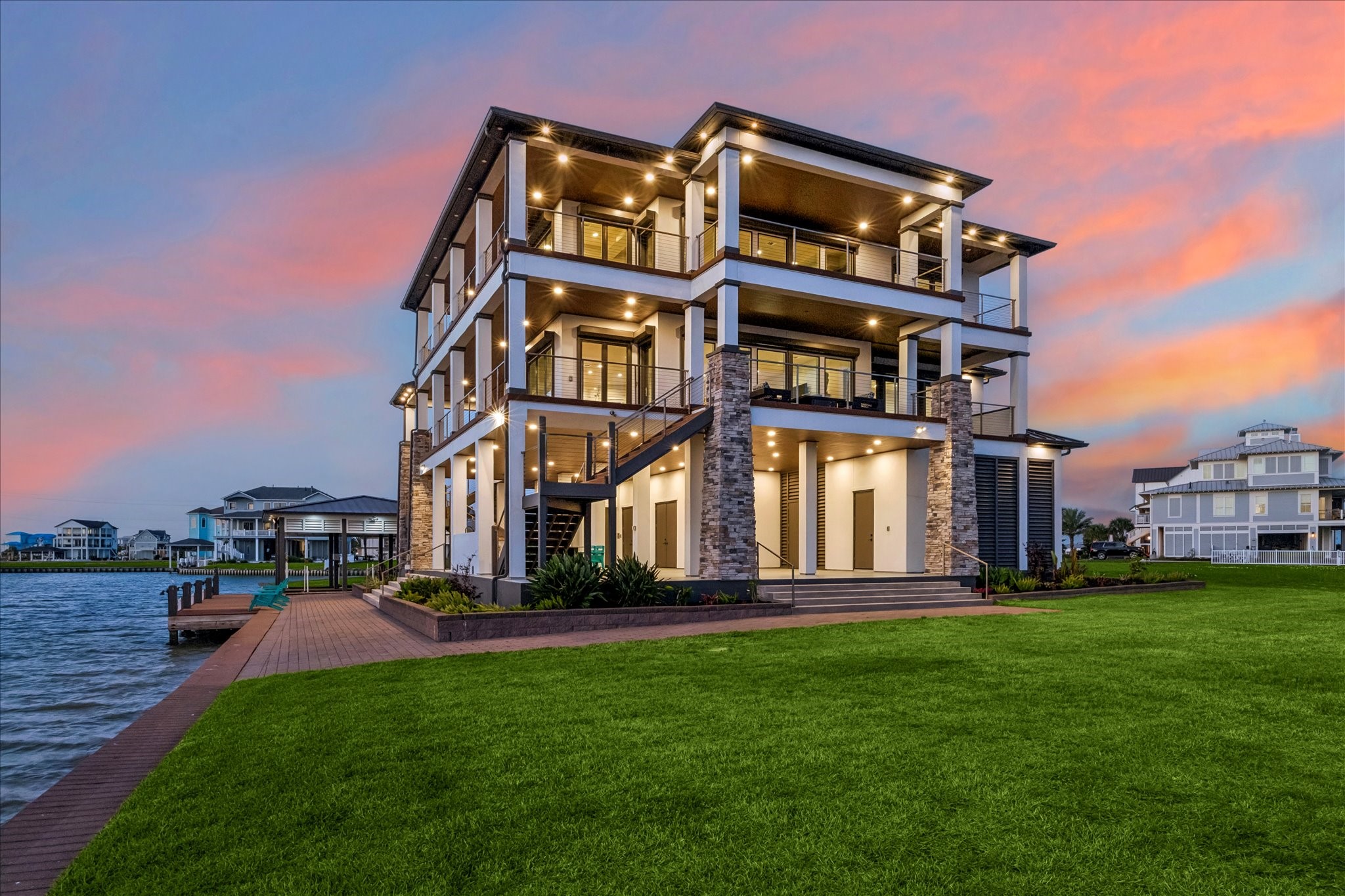 The exterior makes a grand statement with a standing-seam metal roof, stone facade, all protected by motorized storm shutters and surrounded by low-maintenance paverstone walkways. Outdoor living is redefined by a massive entertainment deck featuring maintenance-free composite decking, sleek cable-and-iron railings for unobstructed panoramic views, a double boathouse with dual lifts, fish cleaning station, and a dockside tackle room. The oversized 2 sided garage will hold multiple cars & a golf cart