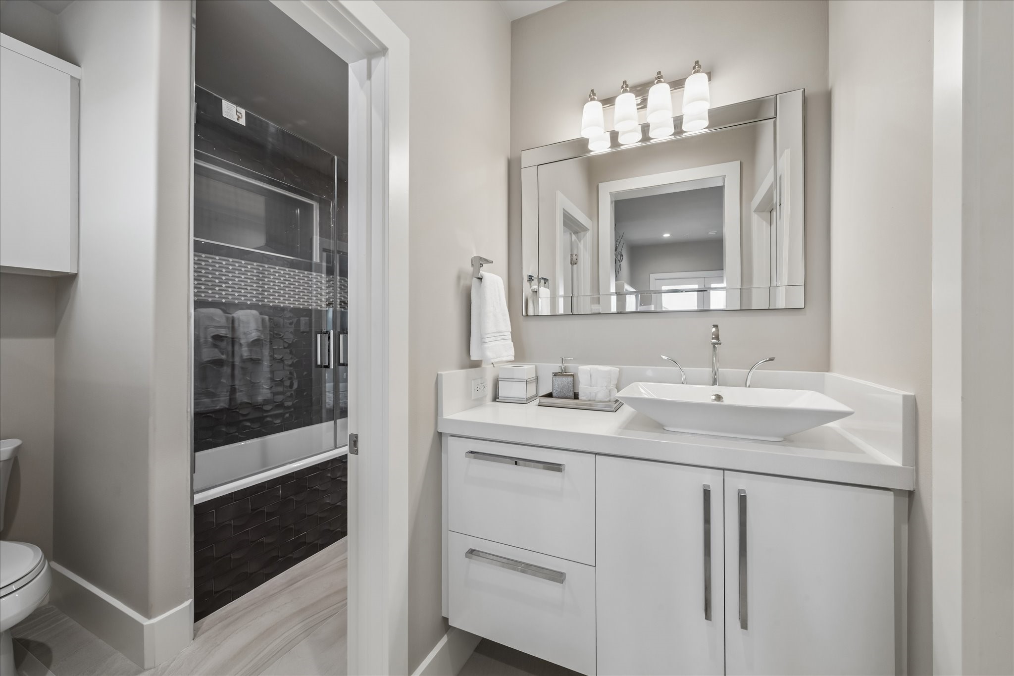 The other side of the Jack & Jill bathroom includes access to the spacious tub/shower, modern fixtures, and a coordinating quartz countertop with under-vanity lighting, offering both style and functionality for the adjoining bedroom