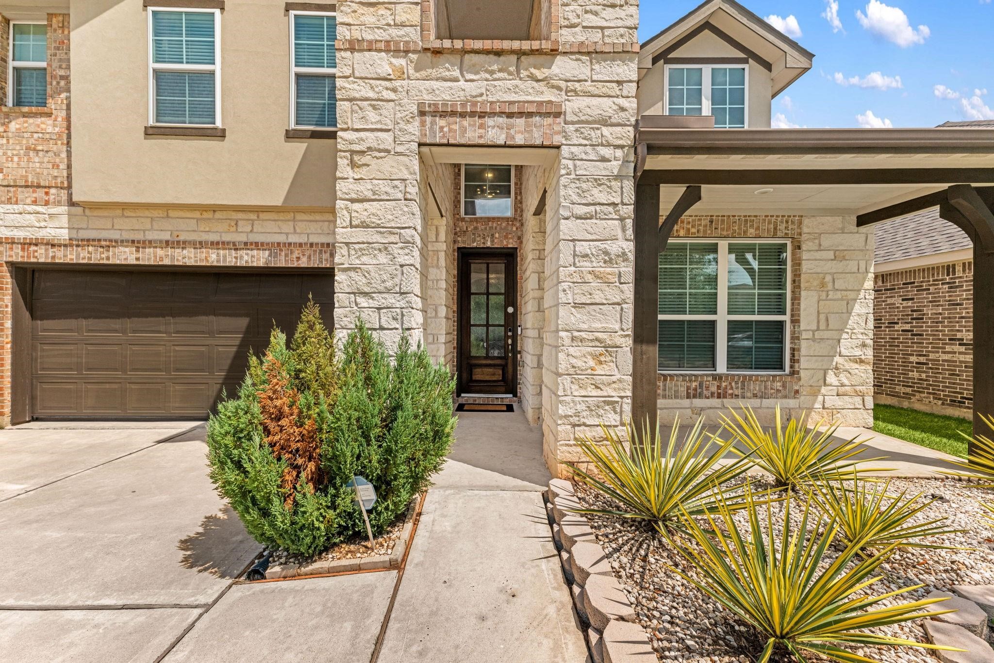 Tall stone columns and a covered porch create a grand yet welcoming front entryway.