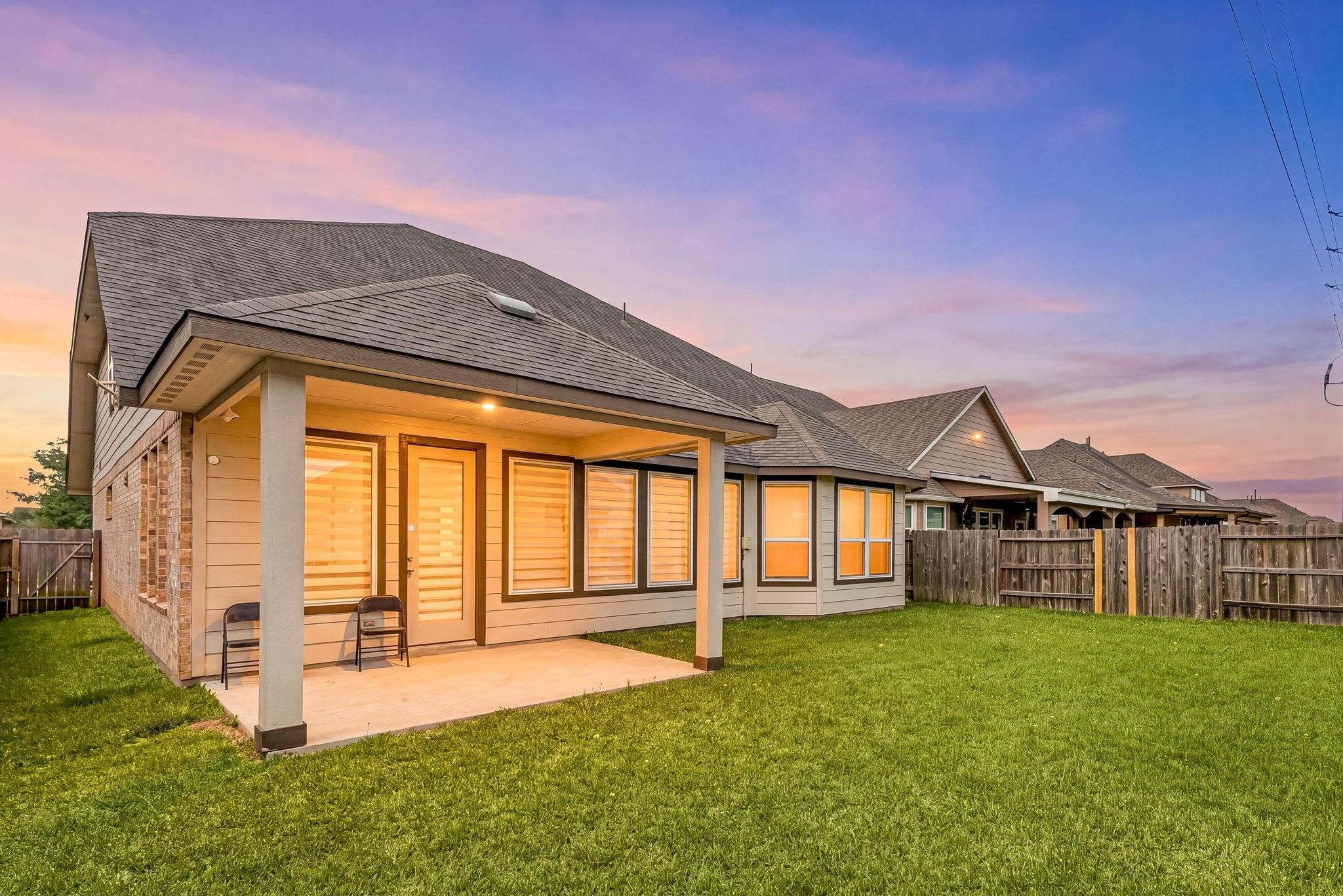 An evening look at the back of the house highlighting the covered patio and clean lines of the rear elevation.