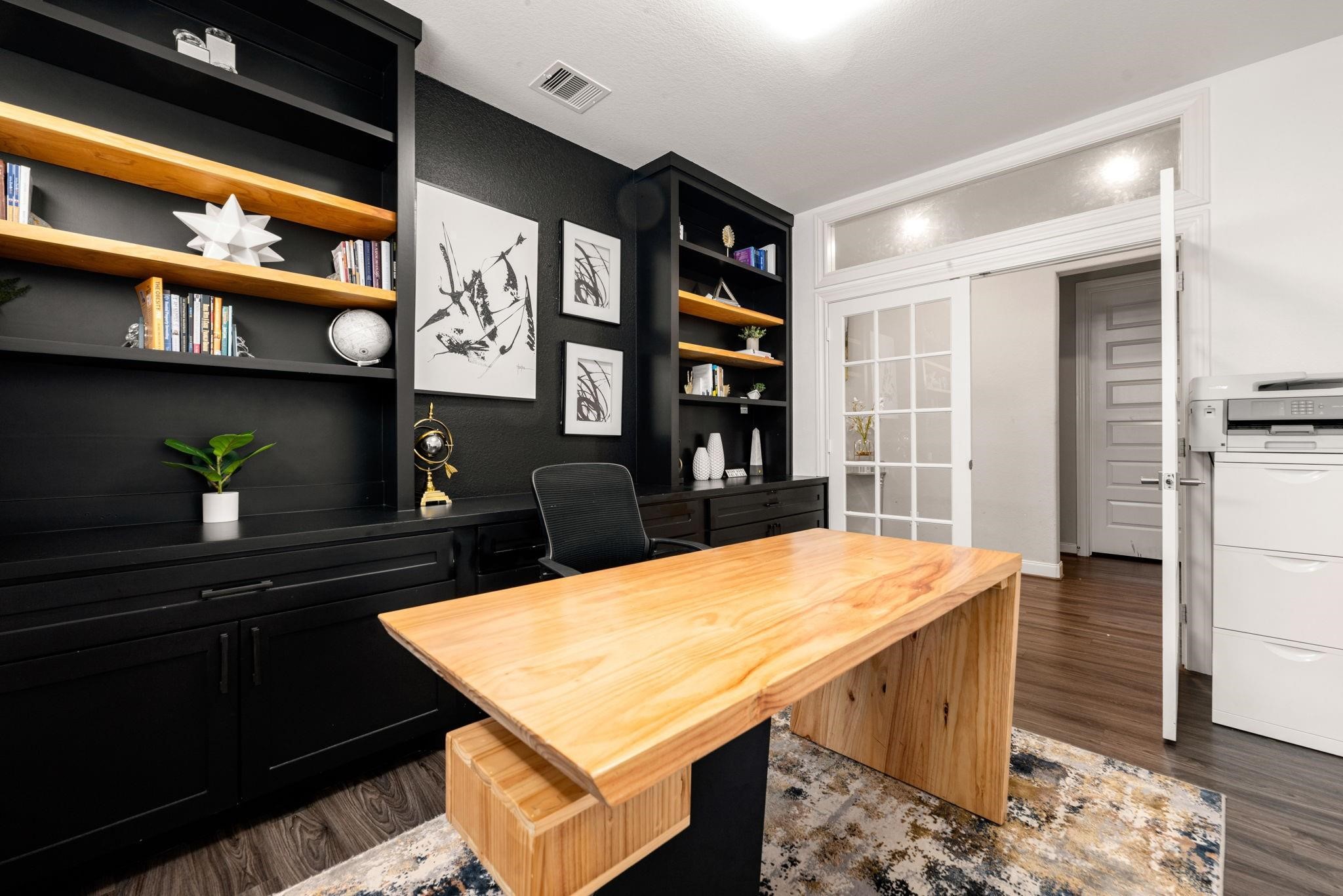 Double doors open to a quiet home office with full-wall built-ins, perfect for working from home.