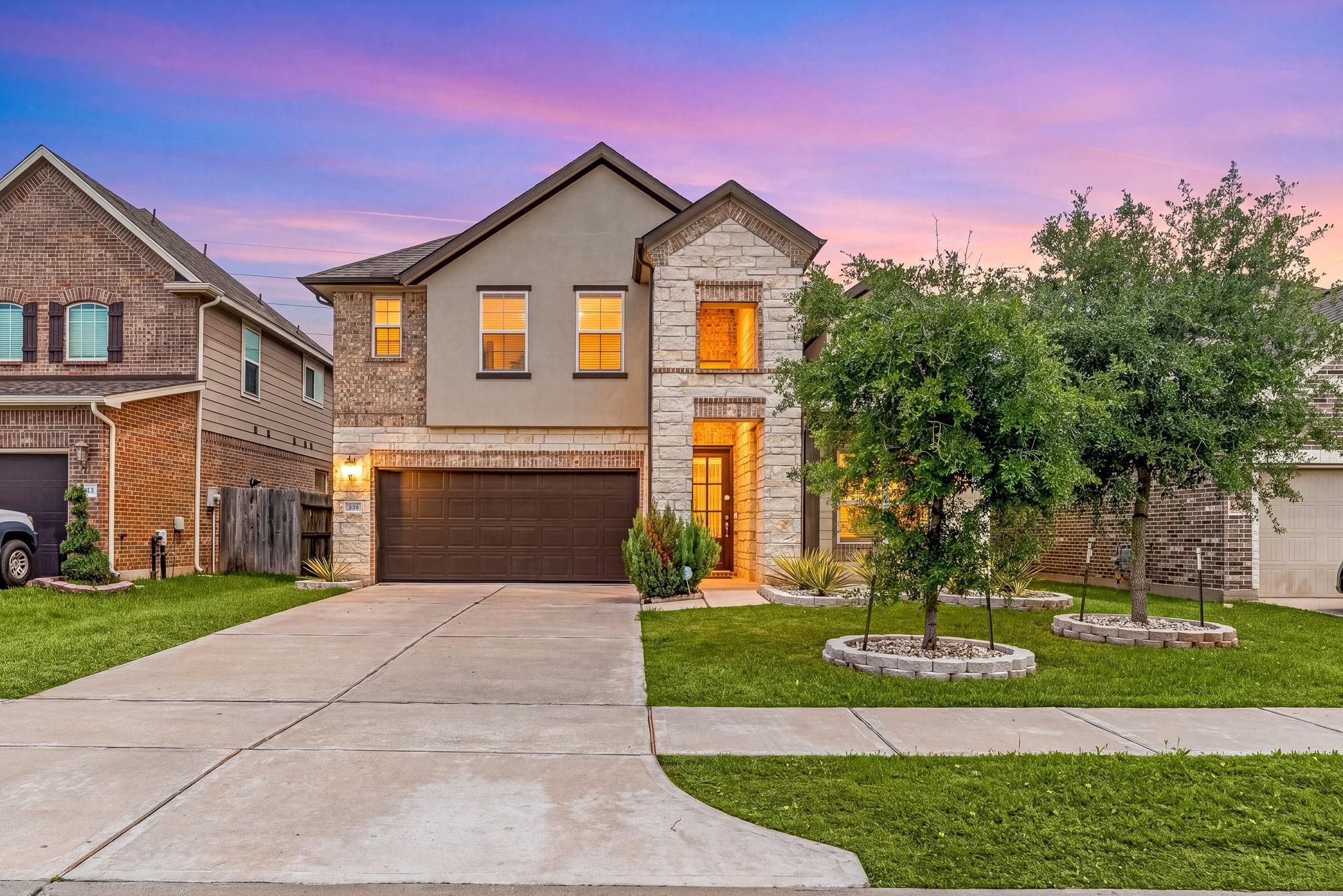 Soft evening light fills the home, showing off the warm brick and stone exterior against the twilight sky. Soft evening light fills the home, showing off the warm brick and stone exterior against the twilight sky.