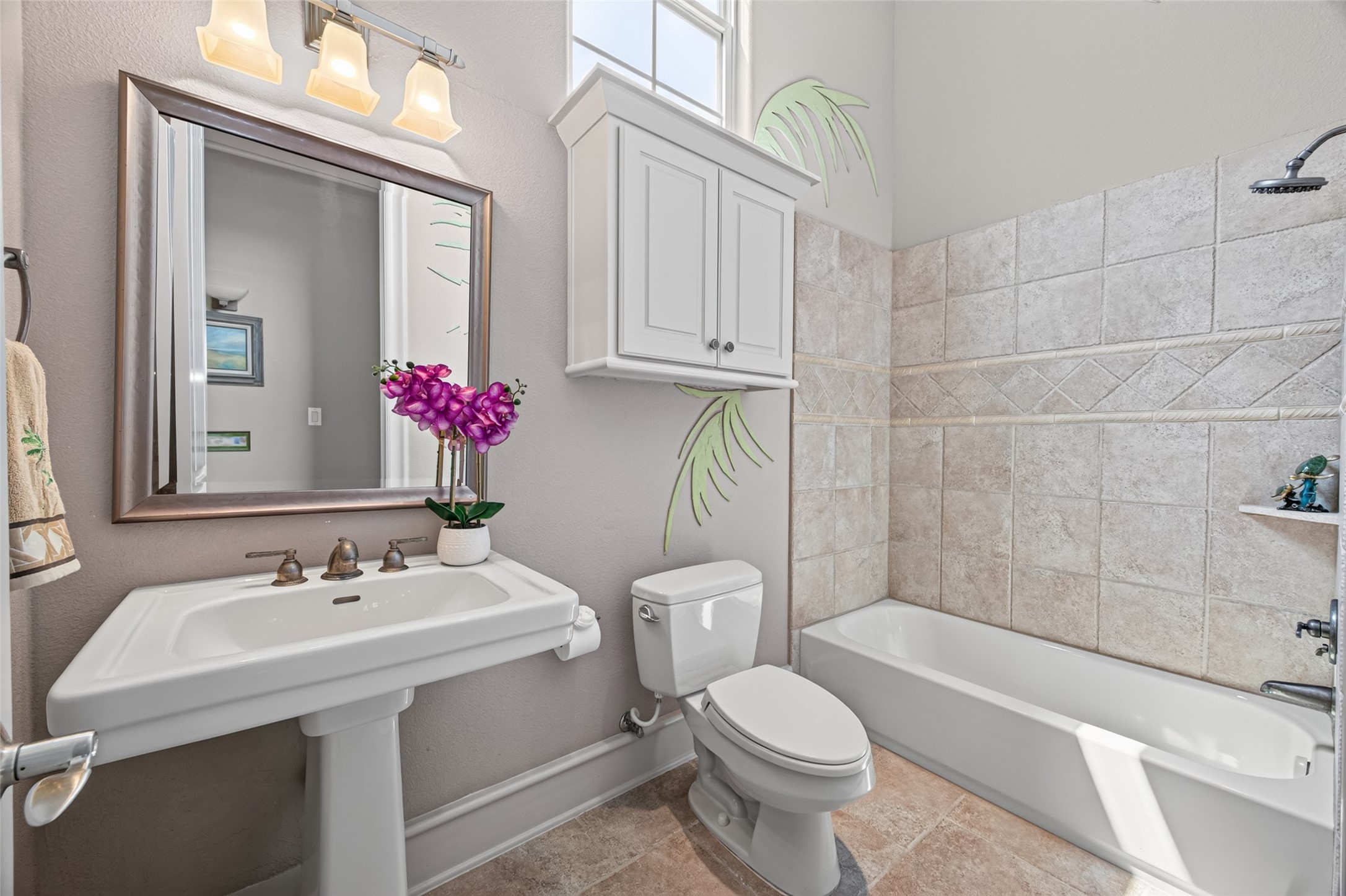 Bright and inviting bathroom with elegant tile work, a spacious bathtub, and a pedestal sink under modern lighting.