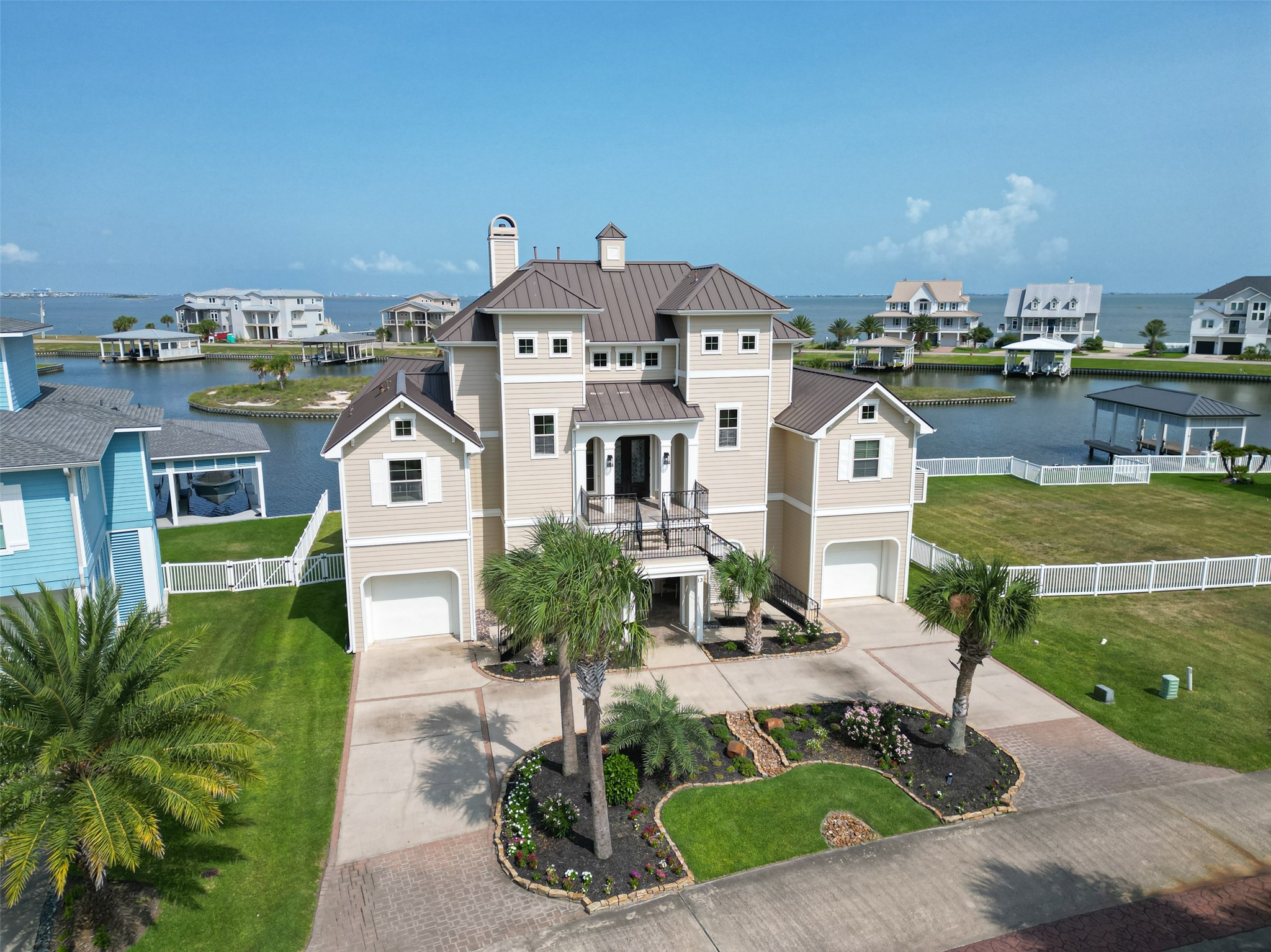 Stunning coastal home with elegant architecture, nestled by serene waterfront views, featuring a beautifully landscaped front yard and spacious dual garages.
