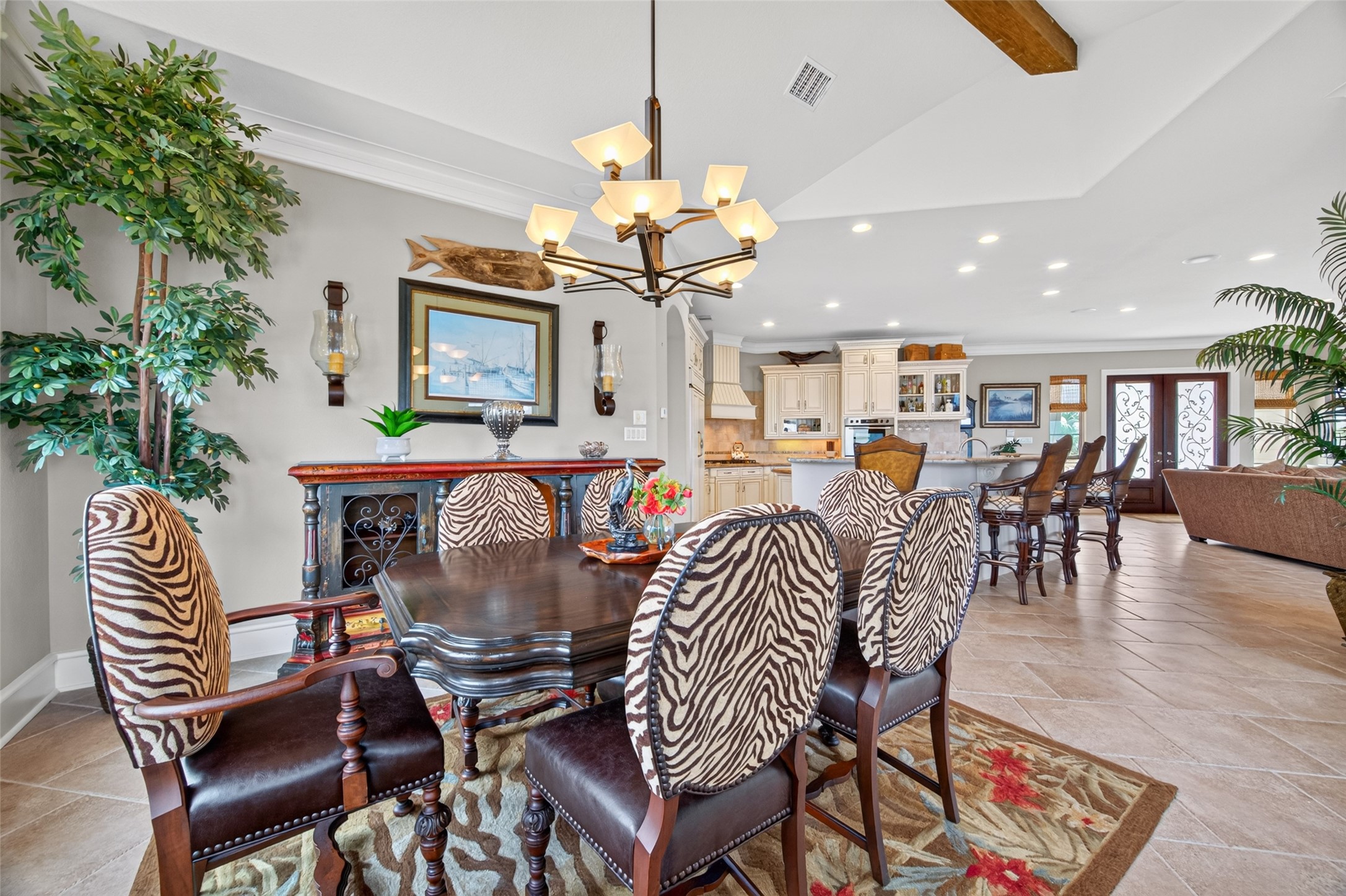 Elegant open-concept dining and kitchen area featuring a stylish chandelier, zebra-patterned chairs, and a spacious layout that flows seamlessly into the living room.