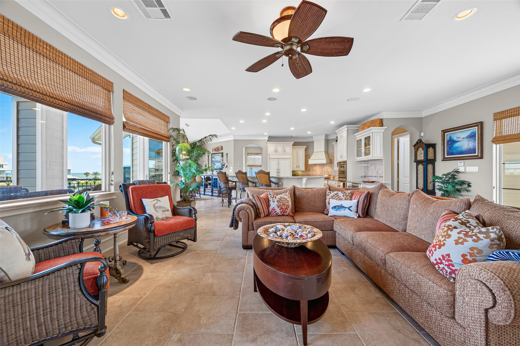 Spacious open-concept living area with abundant natural light, featuring a cozy sectional sofa, elegant ceiling fan, and a seamless flow into the modern kitchen, perfect for entertaining.