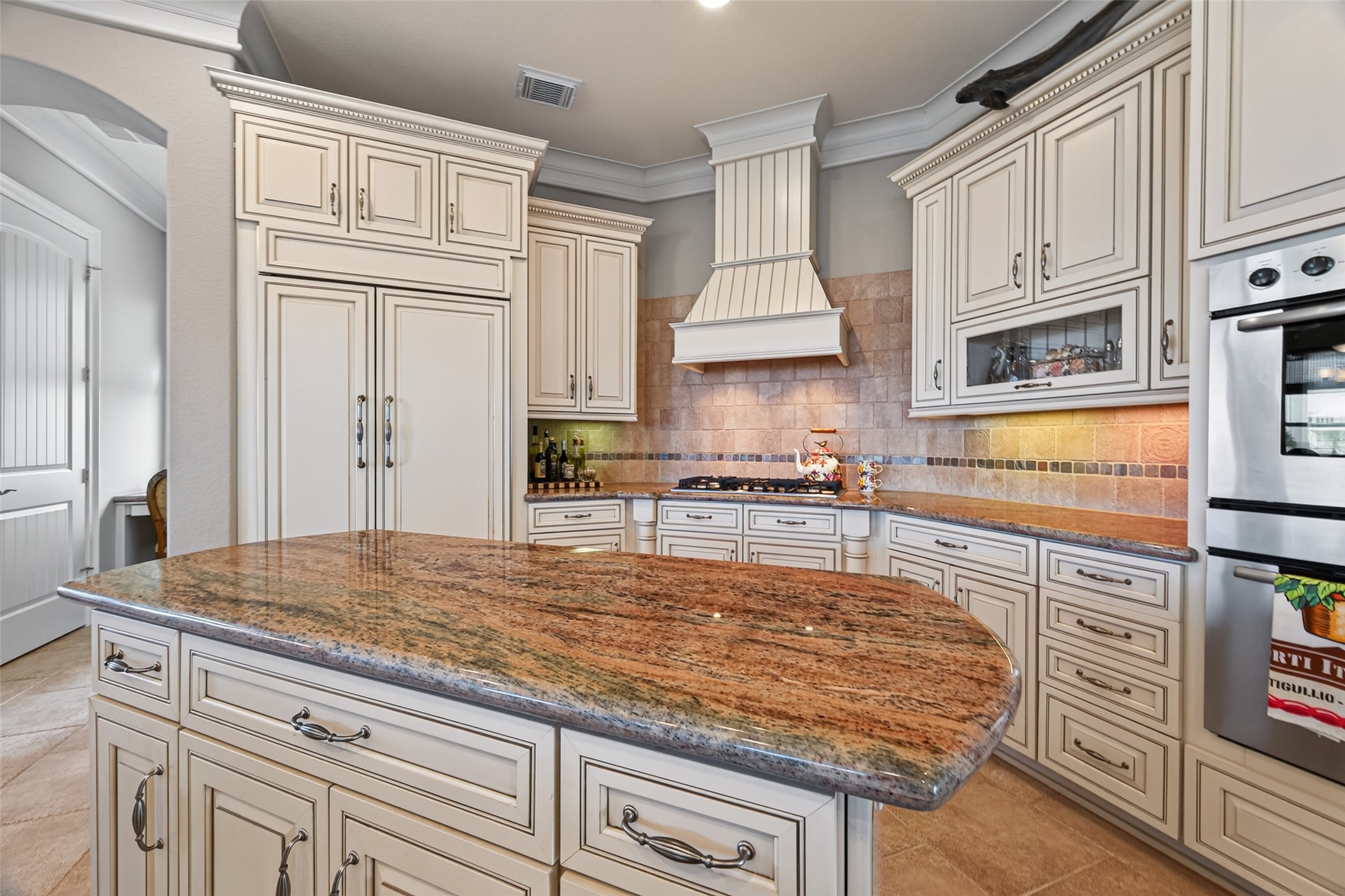 Elegant kitchen featuring custom cabinetry, a sleek granite island, and a stylish range hood, perfect for culinary enthusiasts.