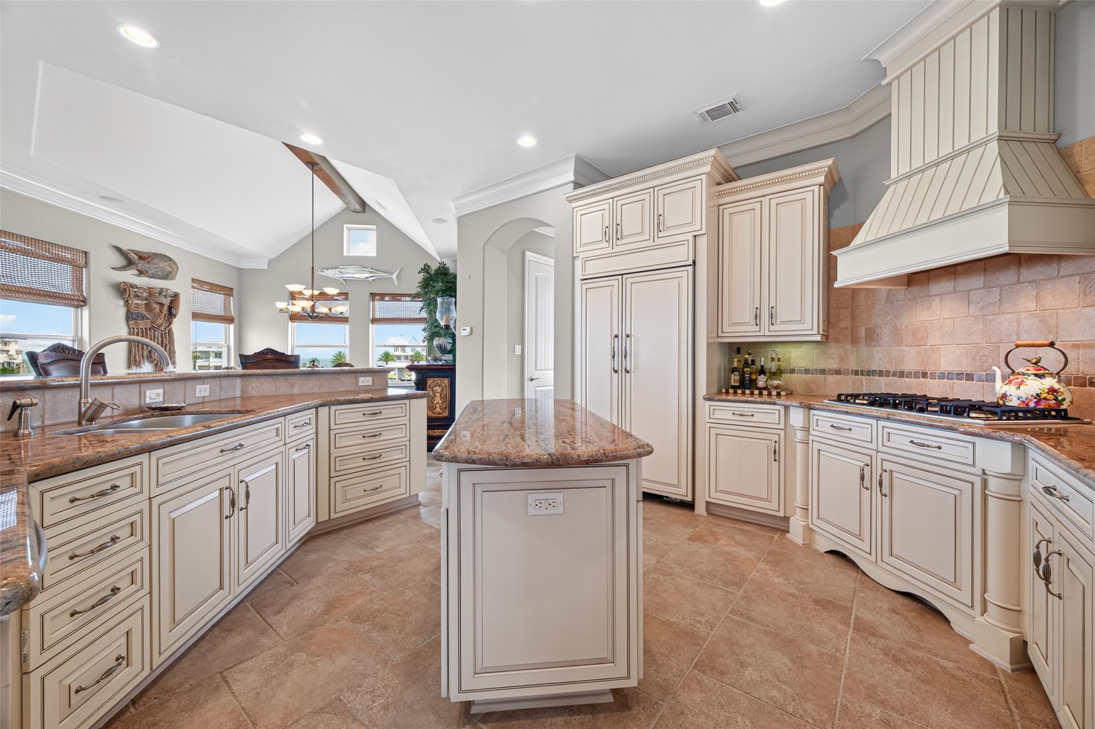 Elegant kitchen featuring custom cabinetry, a spacious island with granite countertops, and a high-end range with a decorative hood.